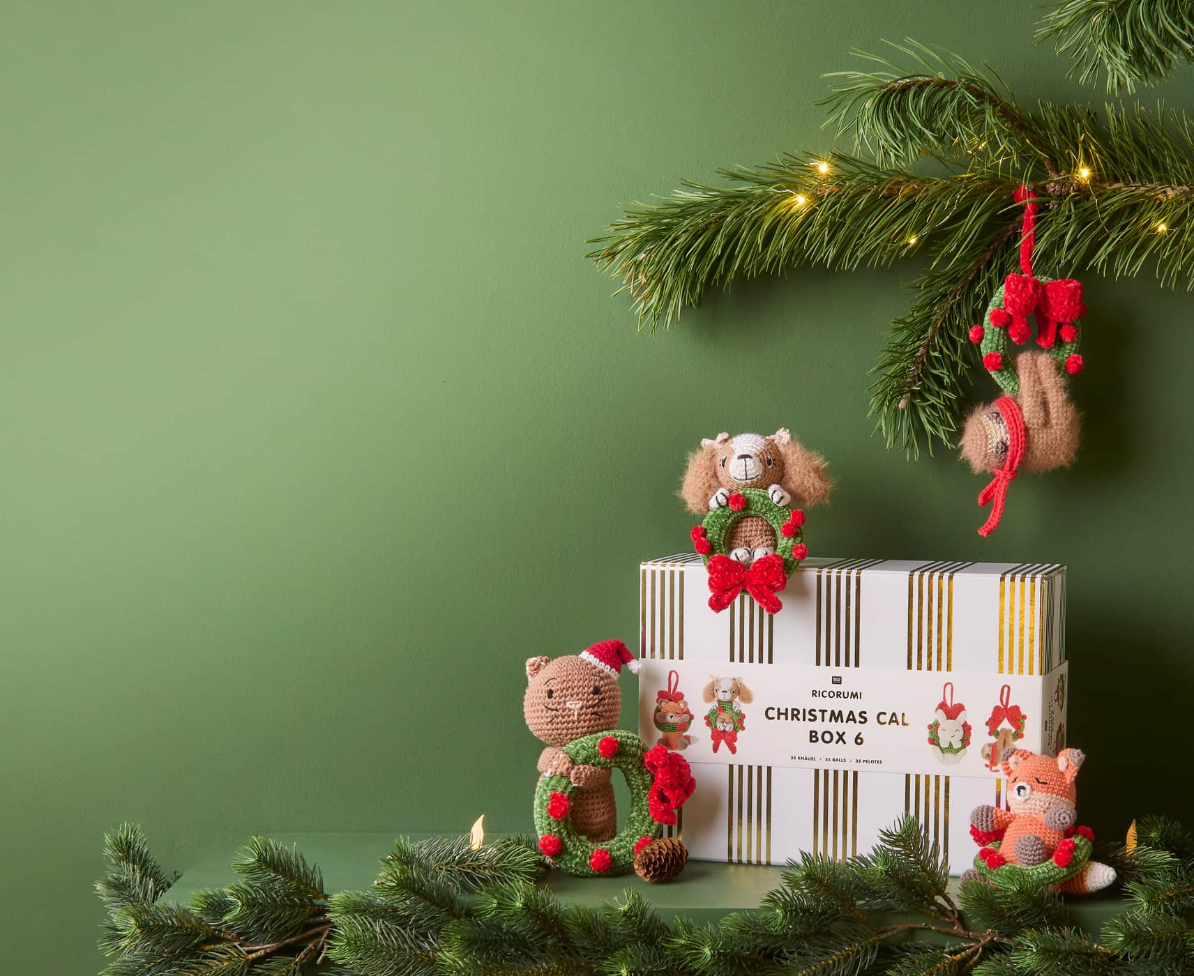 Ricorumi Xmas CAL Box 5 steht vor dunkelgrünen Wänden und ist umgeben von Häkelfiguren.