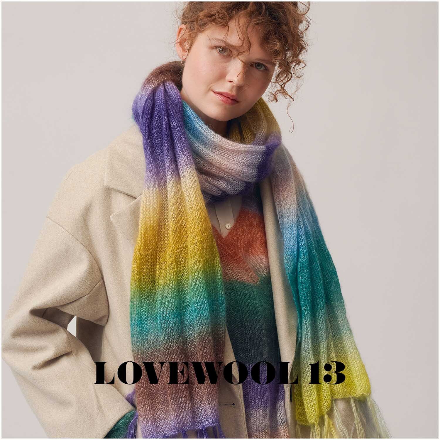 Essentials Super Kid Mohair Loves Silk Print: Frau trägt bunten Schal aus Mohair-Seide-Mischung von Rico Design, ideal für den Winter.