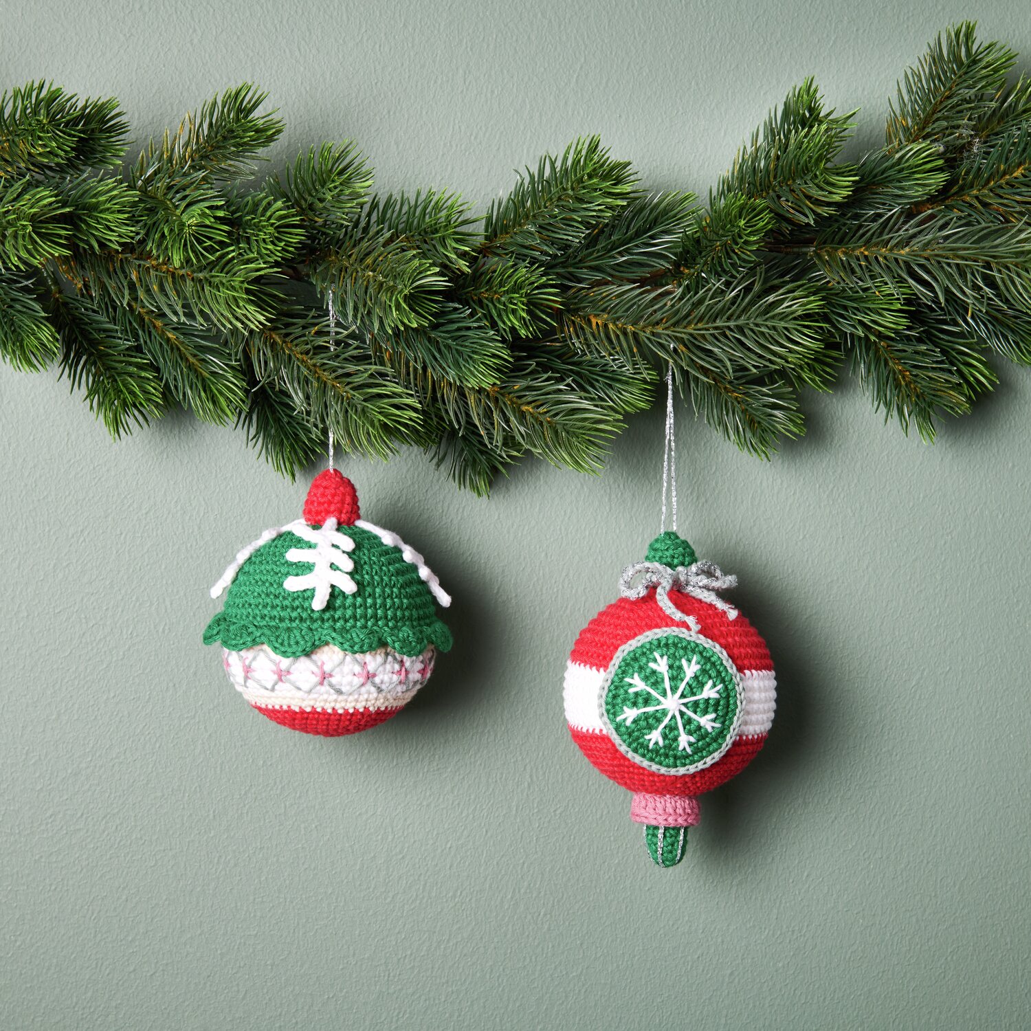 Ricorumi Häkelset Christbaumkugeln Silber: Zwei gehäkelte Kugeln in Rot und Grün an Tannenzweigen.