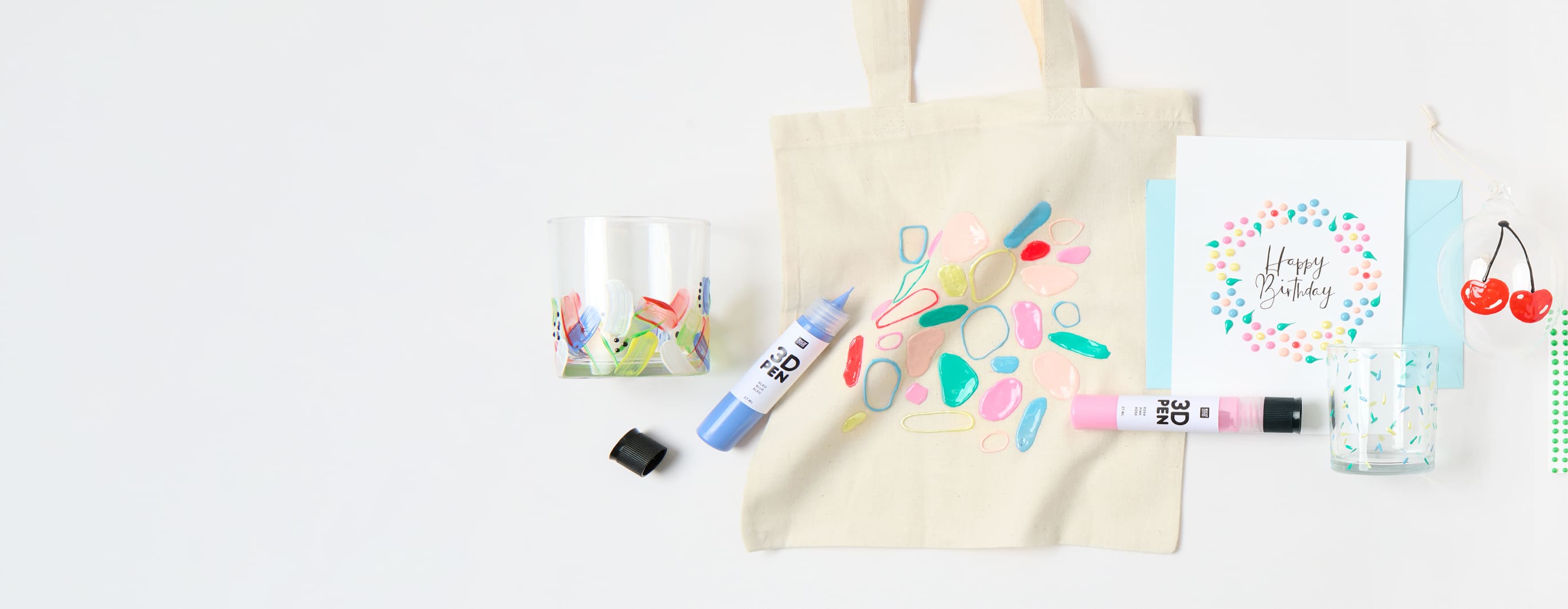 Bunt bemalte Karten, Taschen und Gläser mit 3D- und Perlen-Effekten, liegen umgeben von bunten 3D-Pens auf grauem Hintergrund.