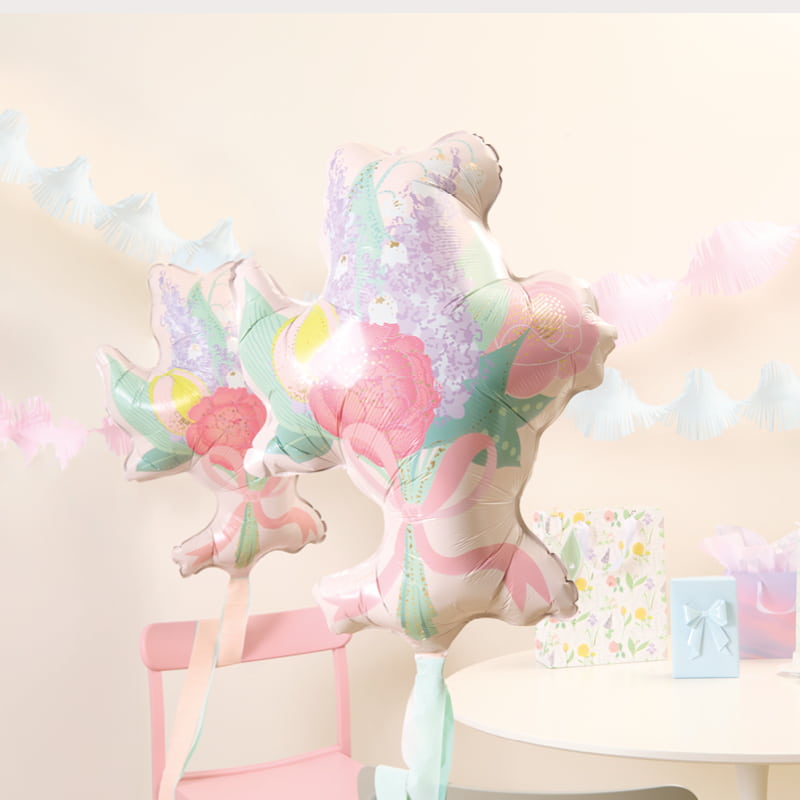 Ein Tisch ist mit Geschenken, Blumenstrauß-Folienballons und Girlanden geschmückt.