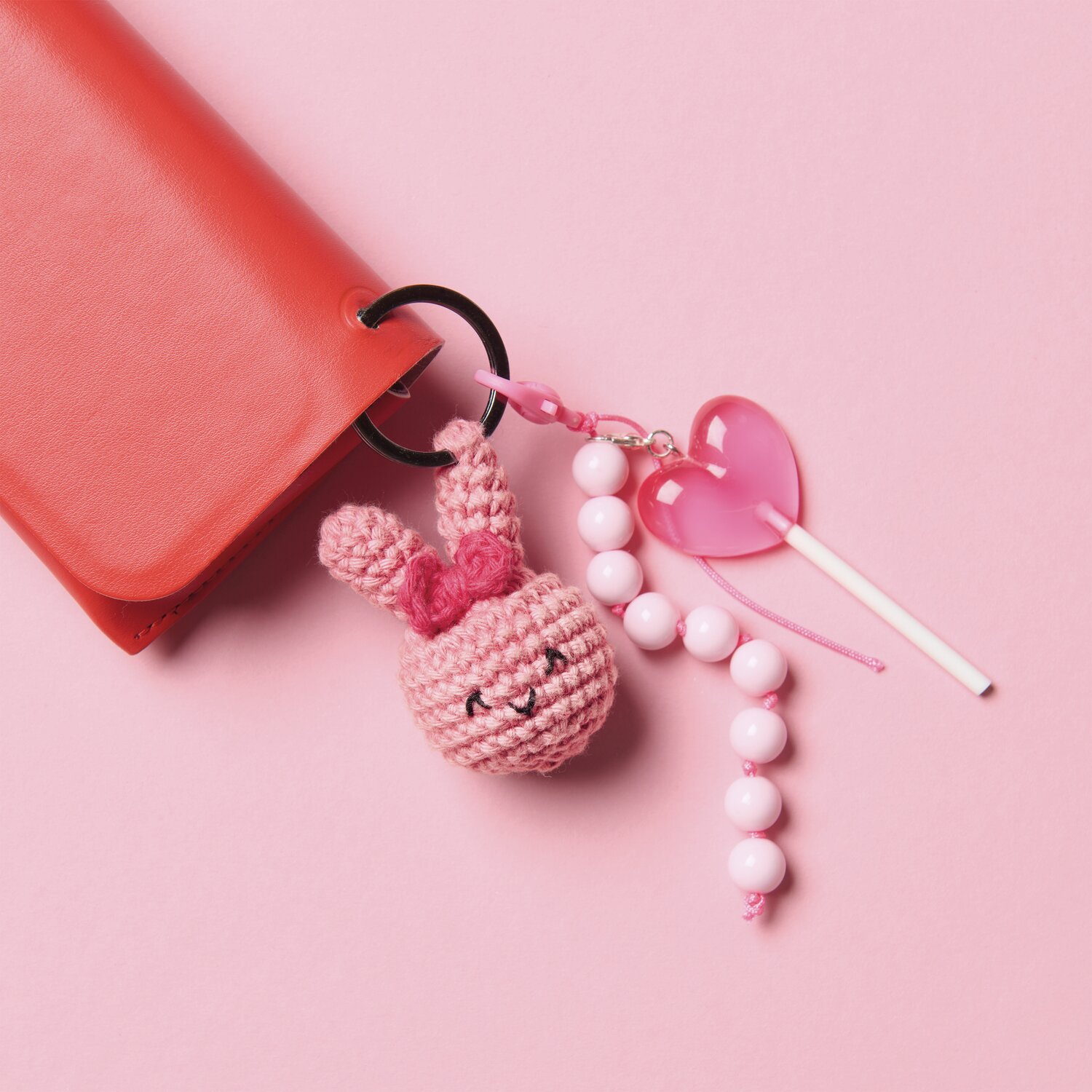 Ricorumi Rico Chingus Schlüsselanhänger mit rosa Häkeltier und Perlen an rotem Etui.