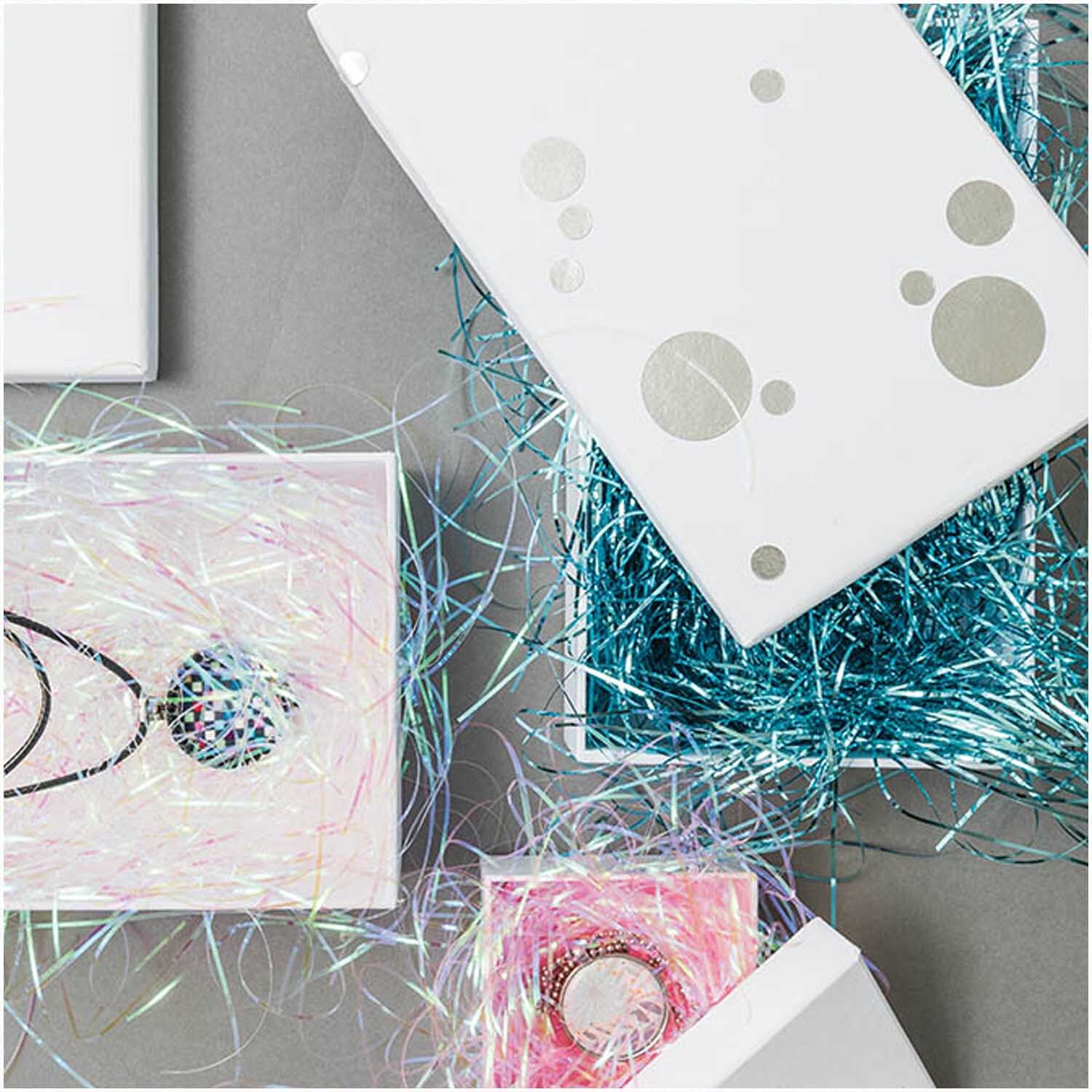 Paper Poetry Füllmaterial Flitter 20g Farbe Irisierend von Rico Design Paper Poetry Füllmaterial Flitter 20g in irisierenden Farben, dekorativ in offenen Geschenkboxen arrangiert. Ideal für kreative Verpackungen.