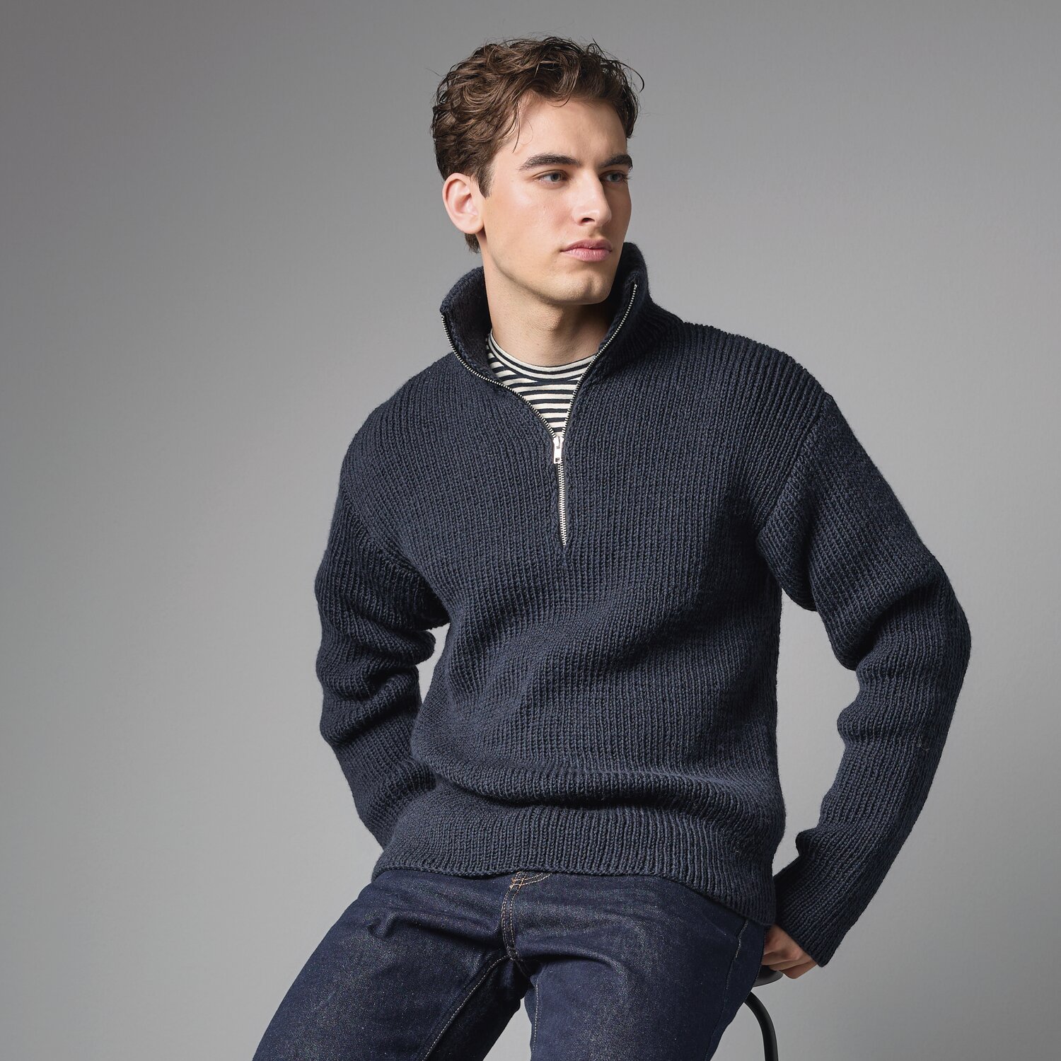 Strickset Pullover Modell 08 aus Made by Me Men No. 3 von Rico Design Strickset Pullover Modell 08 aus Made by Me Men No. 3: Dunkelblauer Pullover mit Reißverschluss, getragen von einem Mann vor grauem Hintergrund.
