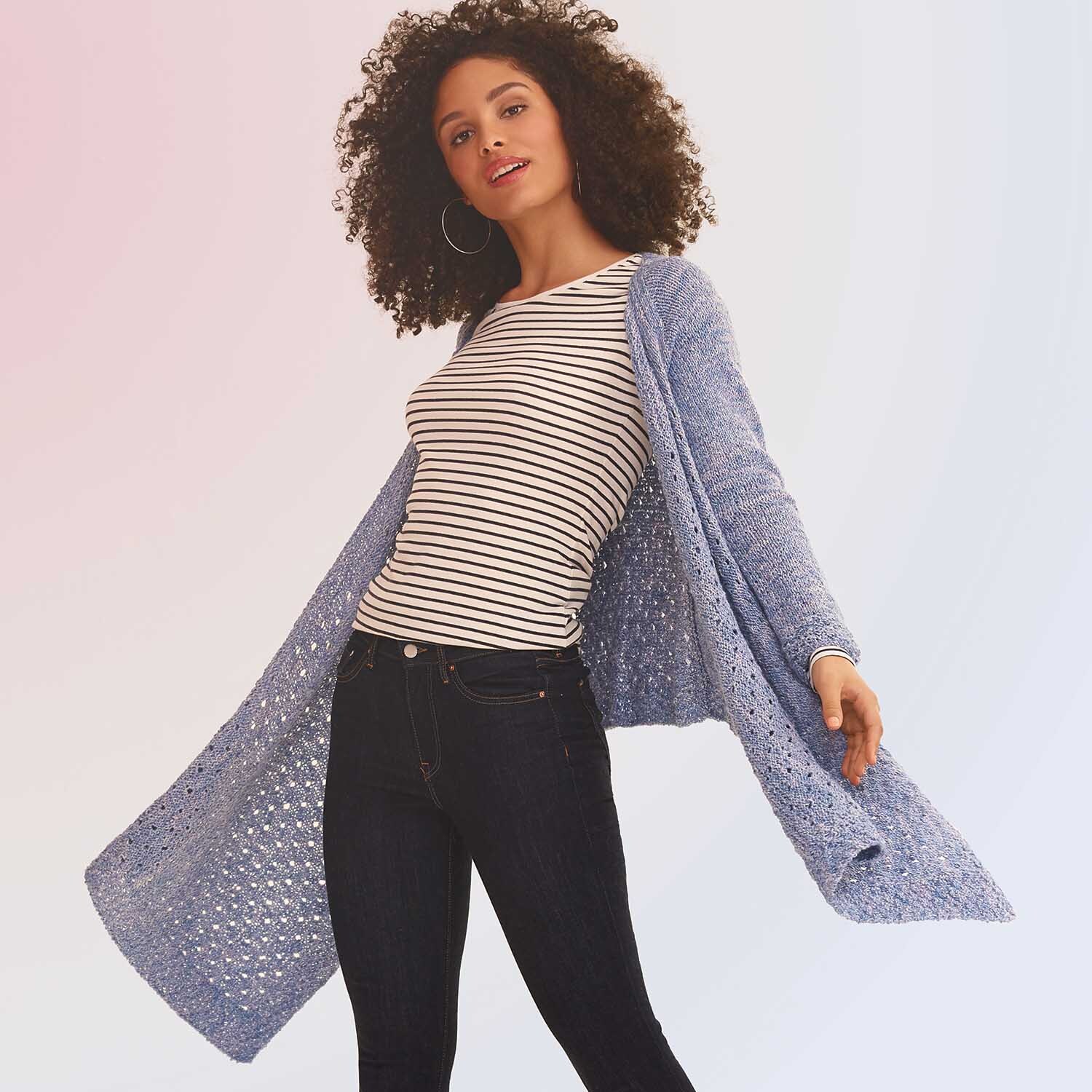 Creative Cotton Zickzack: Frau trägt langen, blauen Strickmantel über gestreiftem Shirt und Jeans.