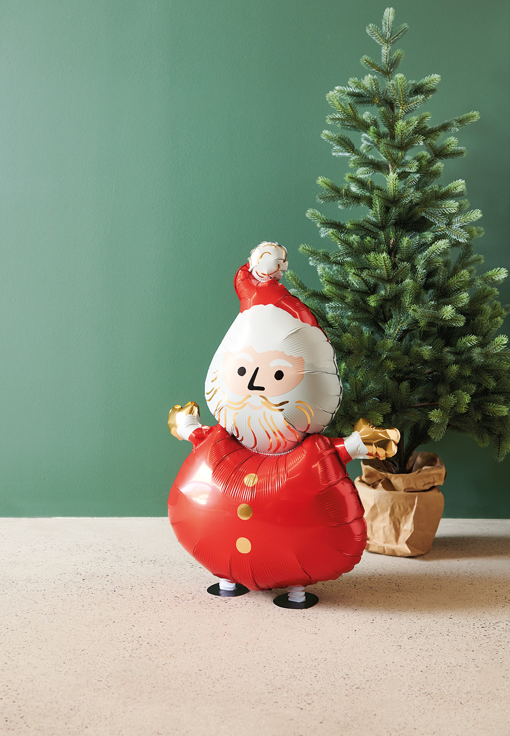 Folienballon im Weihnachtsmann-Design steht vor einem Tannenbaum