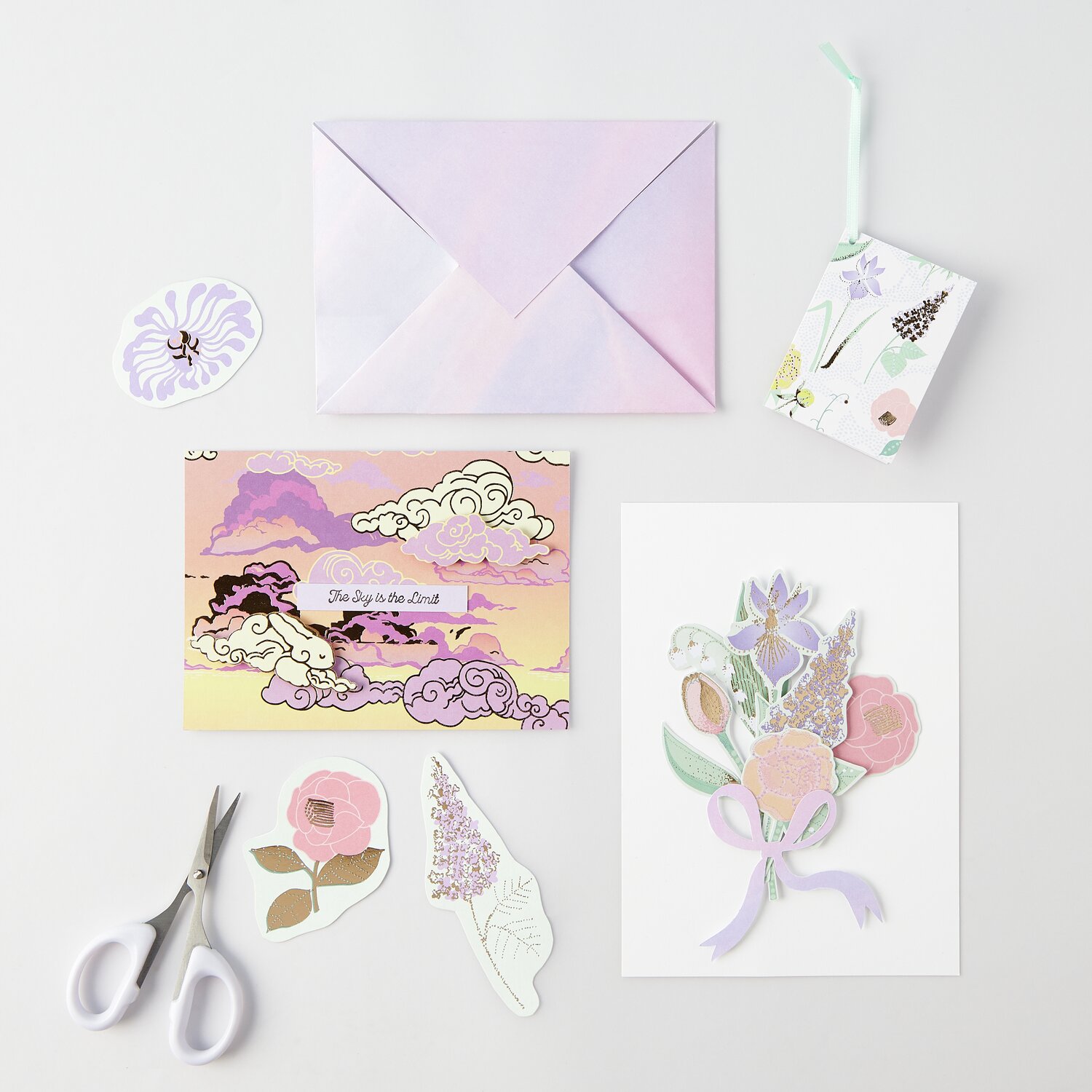Paper Poetry Motivpapierblock The Sky is the Limit: Pastellfarbene Karten, Umschlag, Sticker und Schere auf hellem Hintergrund.