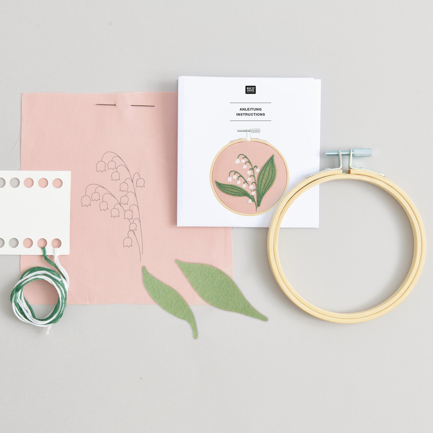 Stickpackung Vorgezeichnet Maiglöckchen: Rosa Stoff mit Maiglöckchen-Muster, Stickrahmen, Garn und Anleitung von Rico Design. Ideal für DIY-Projekte.
