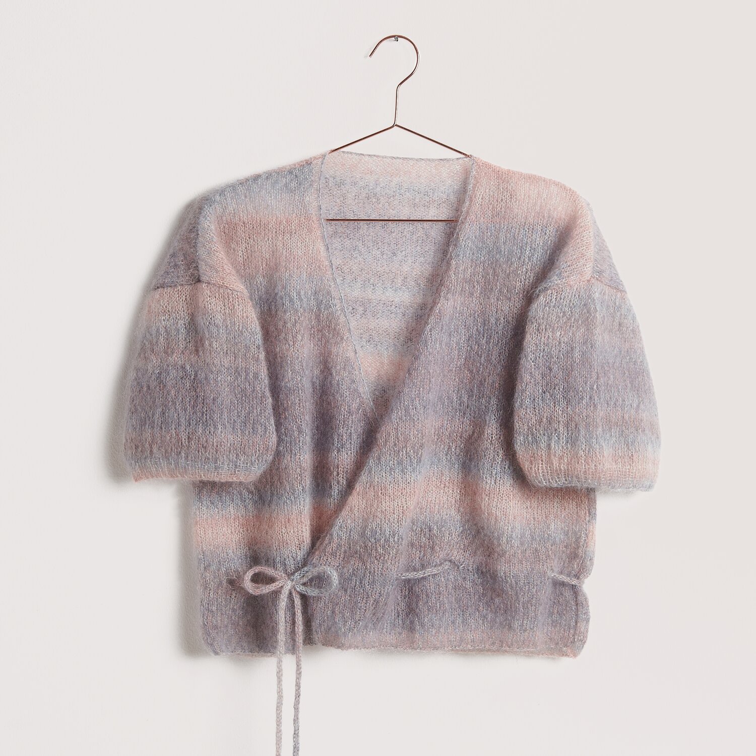 Die Neue Masche No. 12: Weiche Strickjacke aus Super Kid Mohair in Pastelltönen, auf einem Bügel.