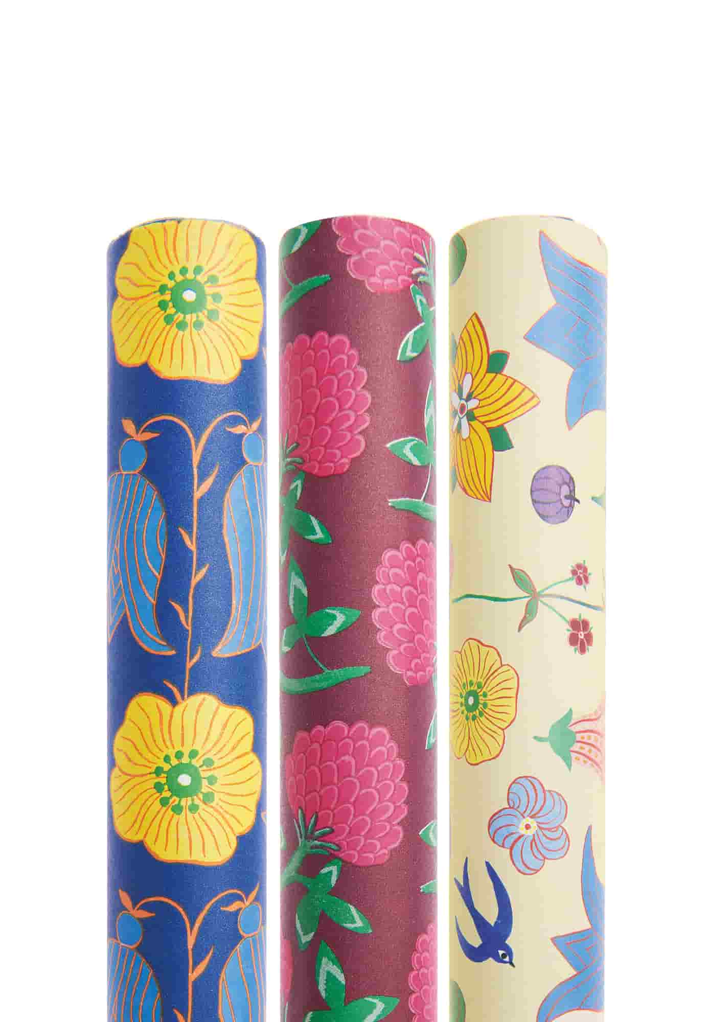 Geschenkpapierrollen mit Illustrationen von Blumen in den Farben Rot, Blau und Gelb