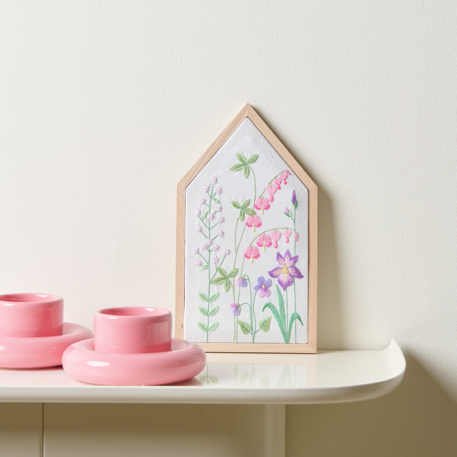 Stickpackung Vorgezeichnet Frühlingshafte Blumenwiese zeigt bunte Blumen in Holzrahmen auf weißem Tisch mit rosa Kerzenhaltern.