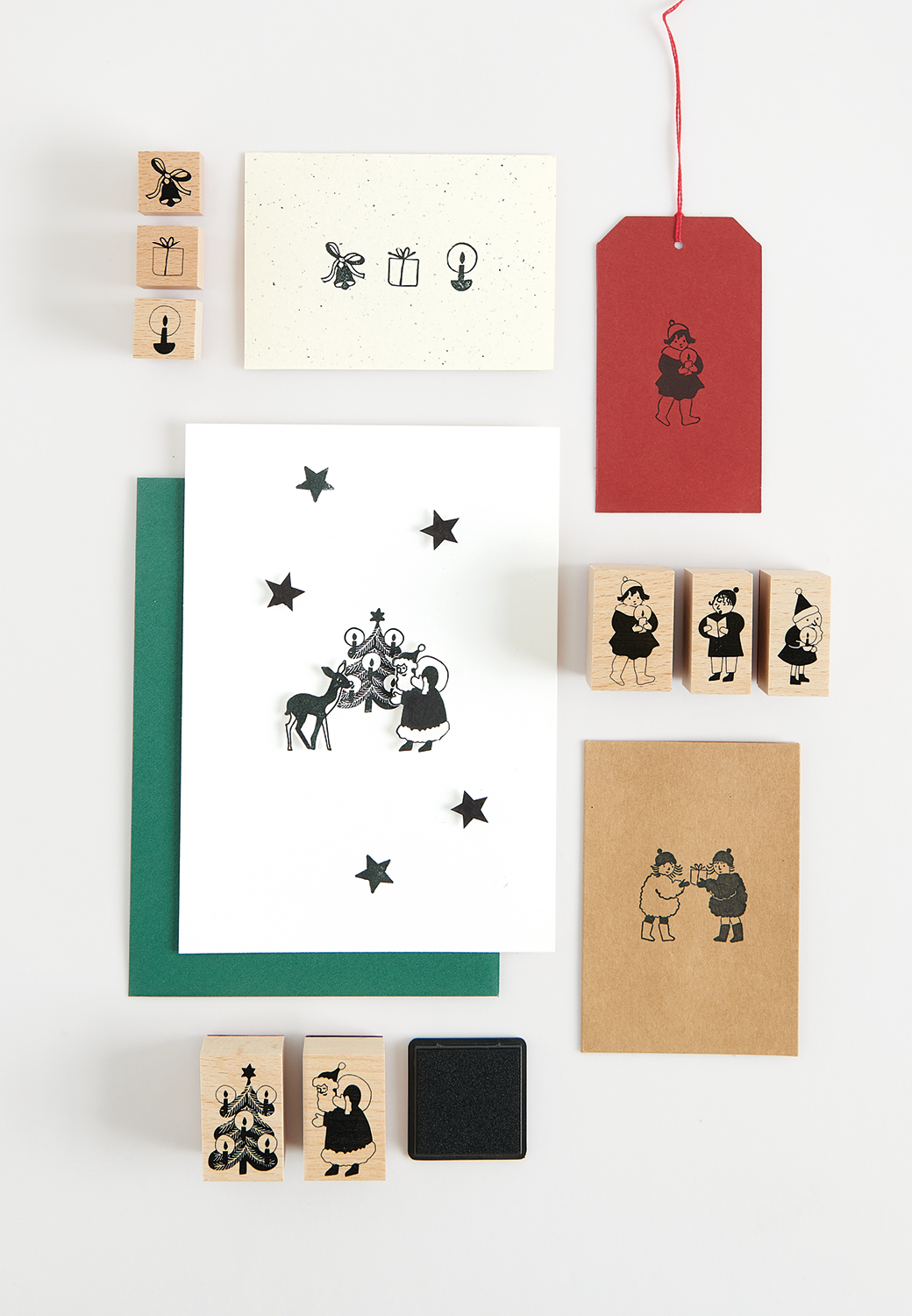 Bestempelte Postkarten mit Weihnachtsfiguren und Umschläge liegen zusammen mit Holzstempel auf grauem Hintergrund 