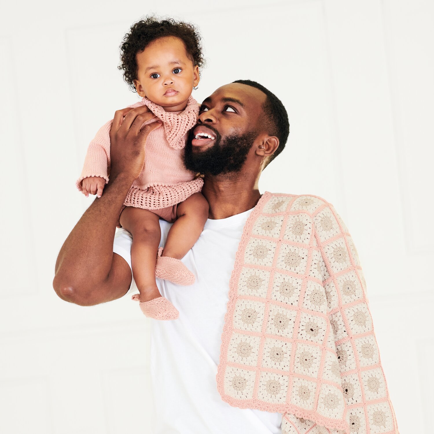 Häkelset Decke Modell 20 aus Baby 043: Vater mit Baby in rosa Strickkleidung und passender Decke.