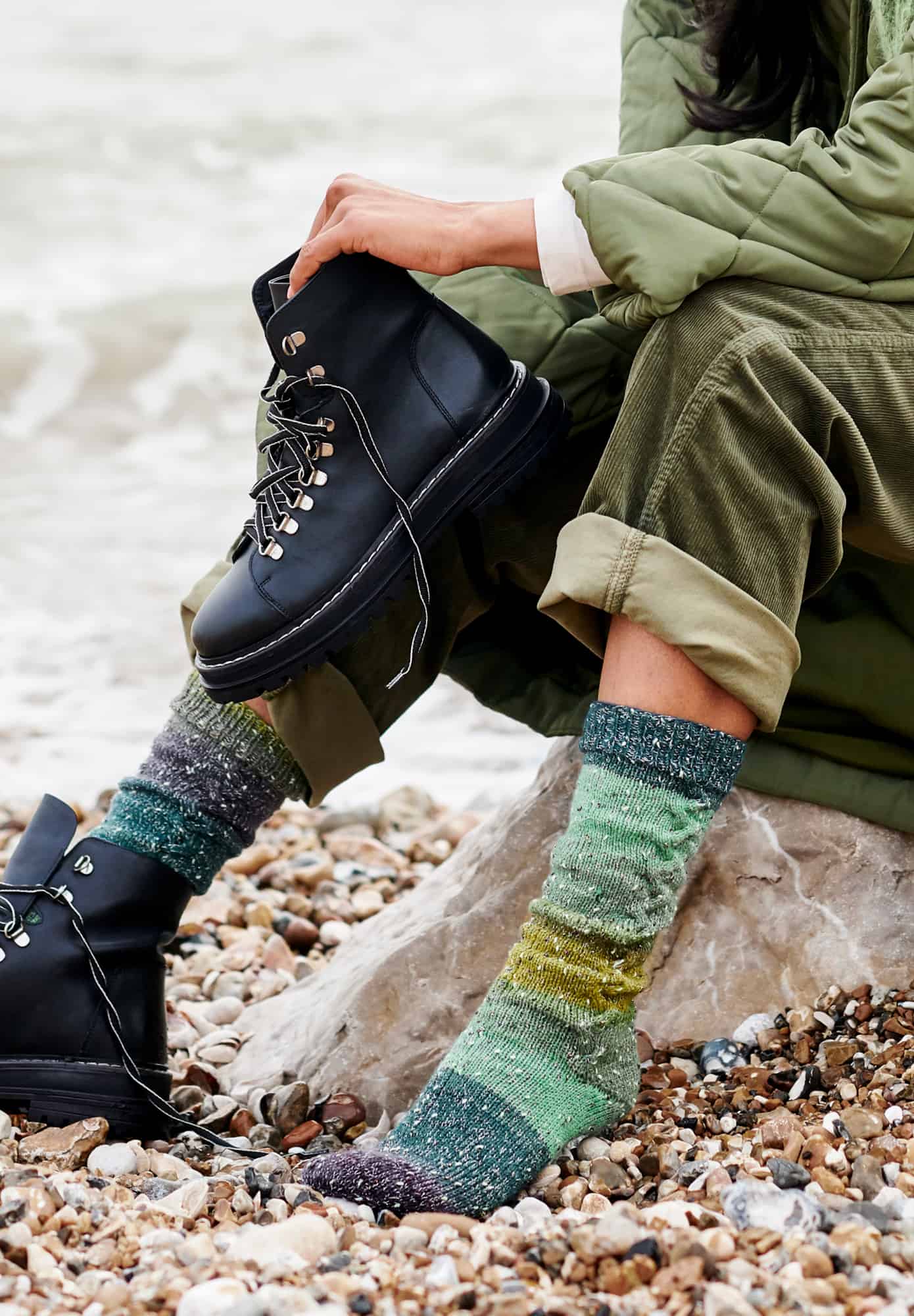 Frau trägt gestrickte Socken in Grüntönen: Modell 08 aus Lovewool No. 21
