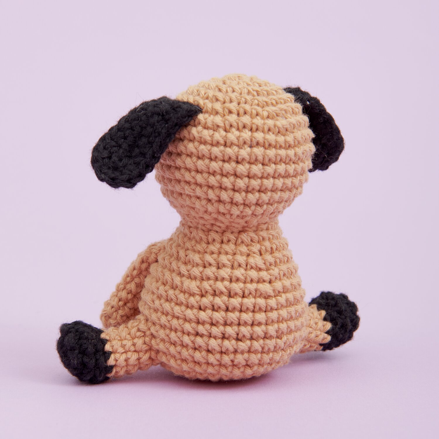 Ricorumi Mini Easy Häkelset - Hund: Beigefarbener, gehäkelter Hund mit schwarzen Ohren und Pfoten auf rosa Hintergrund. Ideal für Anfänger.