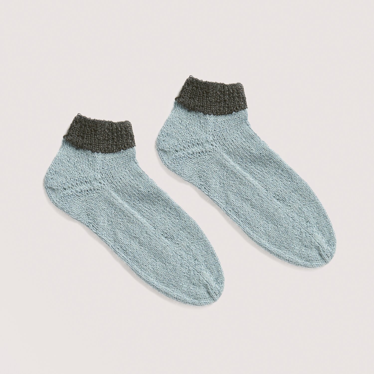 Luxury Knits - Premium Natural Fibres Sprachauswahl deutsch von Rico Design Strickset Socken Modell 10 aus Luxury Knits, hellblaue Socken mit dunkelgrauem Bündchen.