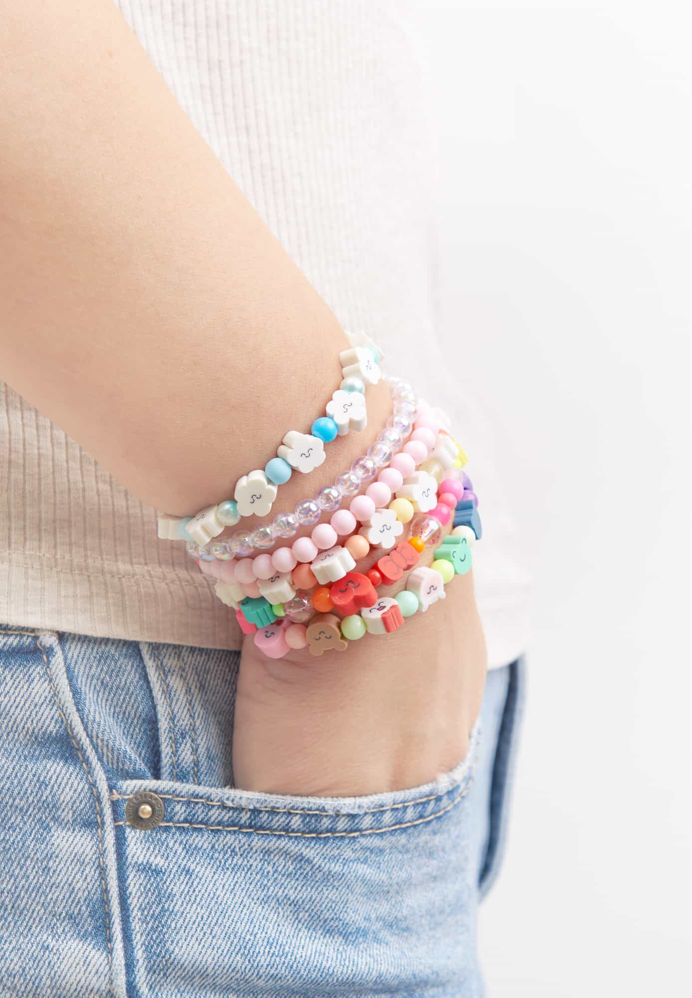 Ein Arm trägt viele Perlen-Armbänder in verschiedenen Designs.