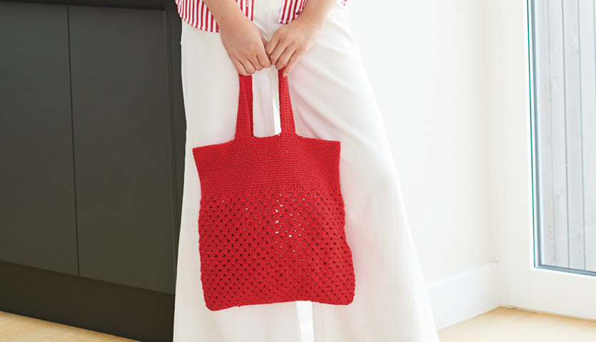 Häkelanleitung Tasche aus Essentials Super Cotton dk: Rote, gehäkelte Tasche in Hand gehalten, ideal für den Sommer.
