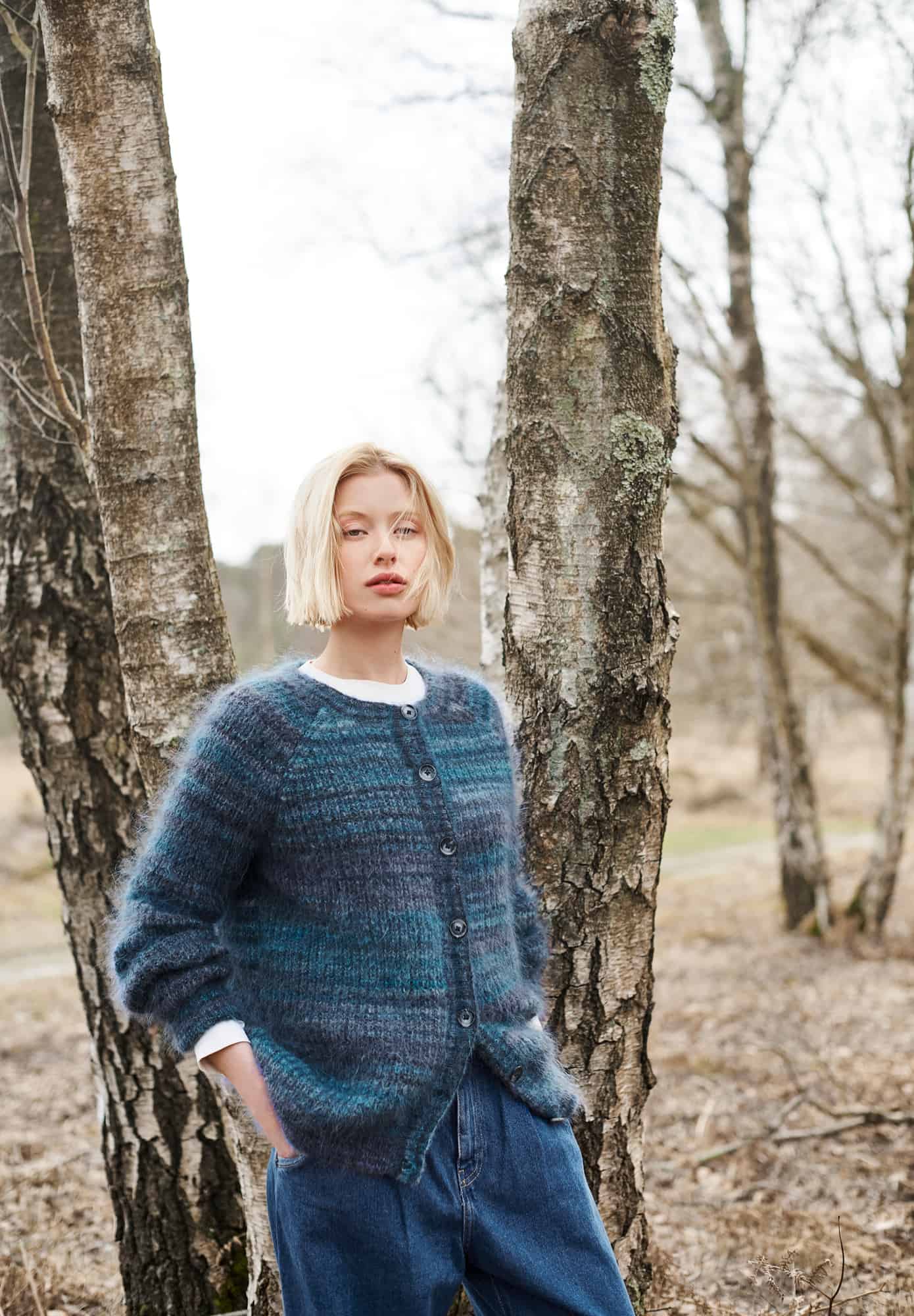 Frau trägt gestrickten Cardigan in Blautönen mit Knopfleiste: Modell 26 aus Lovewool No. 21