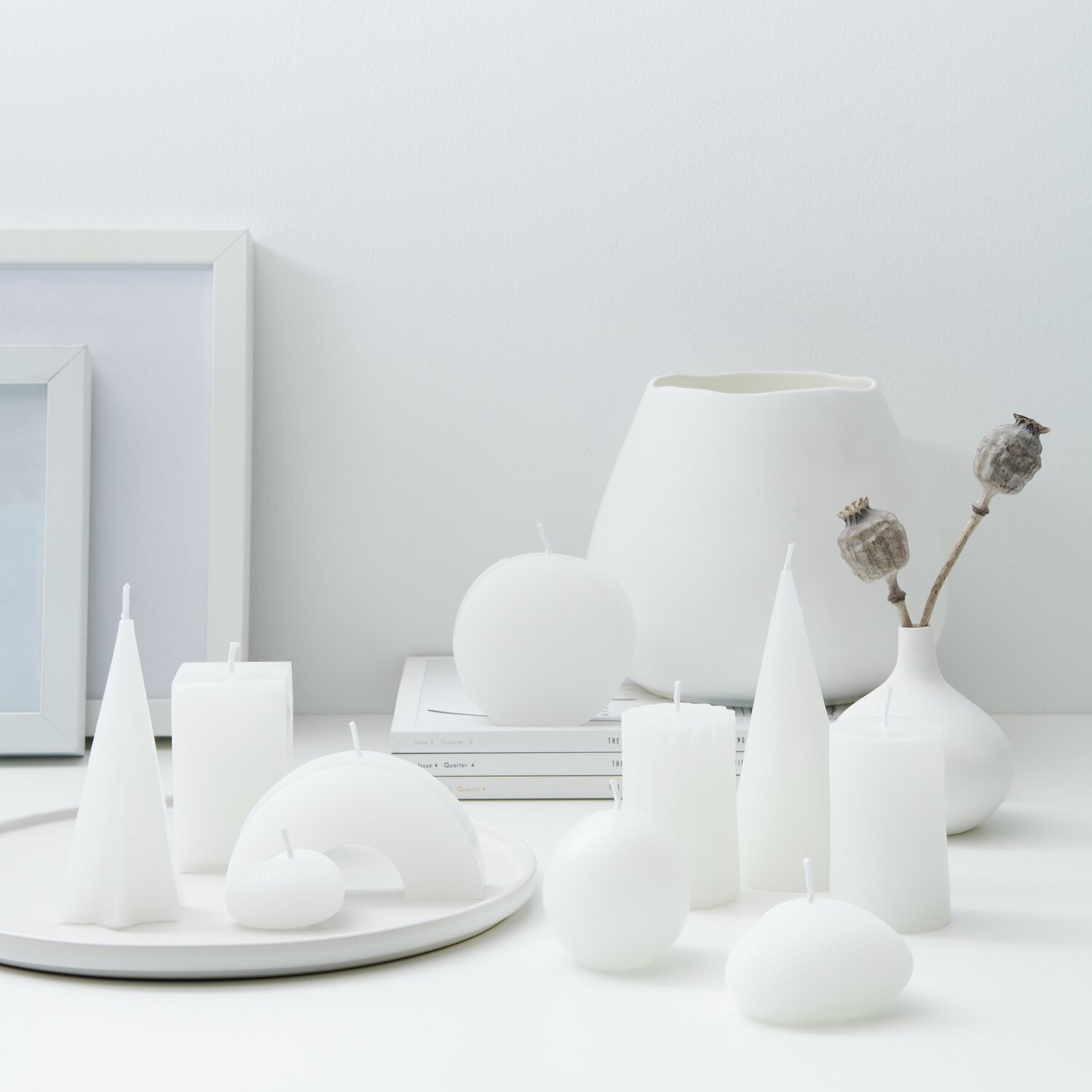 Kerzenwachs Pastillen, 1000g: Verschiedene weiße Kerzenformen auf einem Tisch, dekorativ arrangiert.