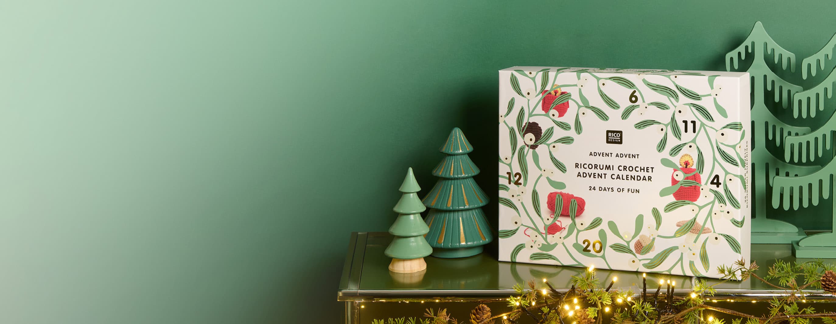 Ricorumi Adventskalender steht auf Kamin, daneben dekorative Bäume