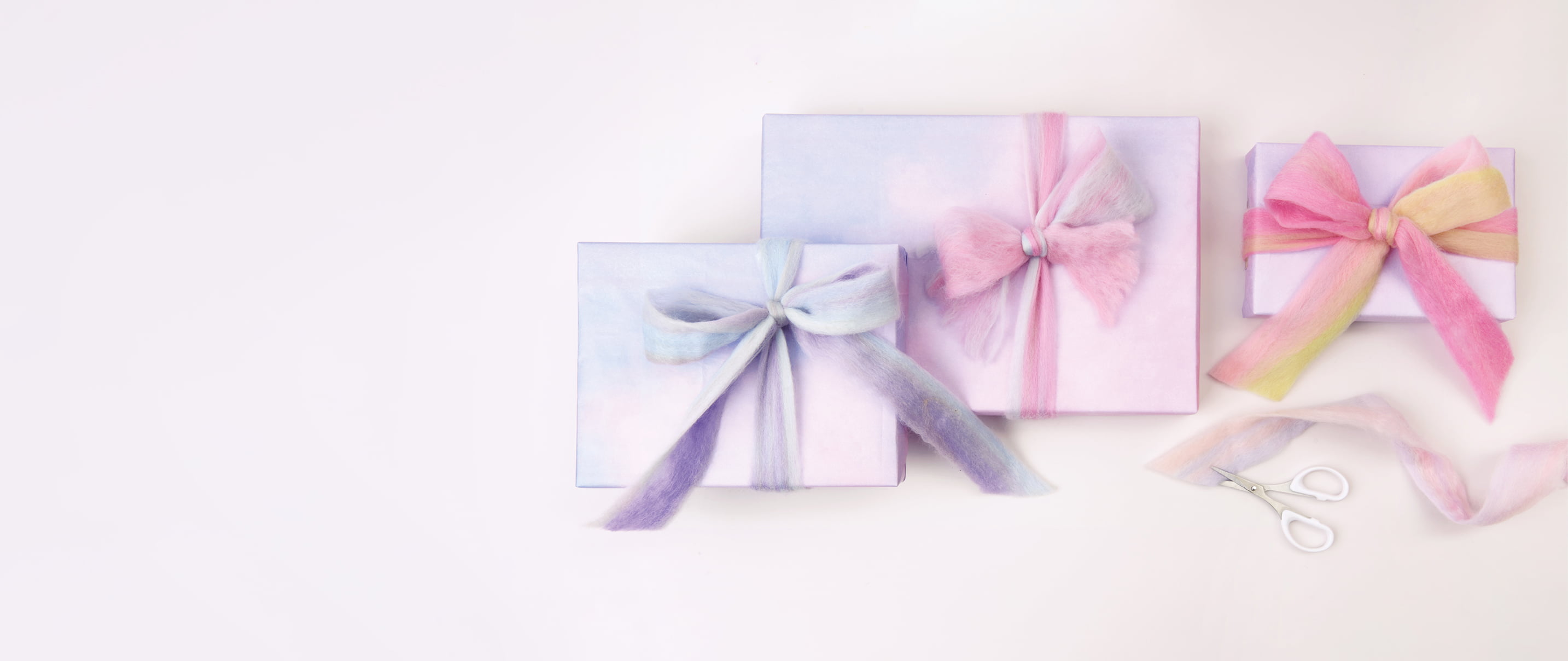 Verpackte Geschenke in Pastelltönen sind mit Filzband geschmückt. 