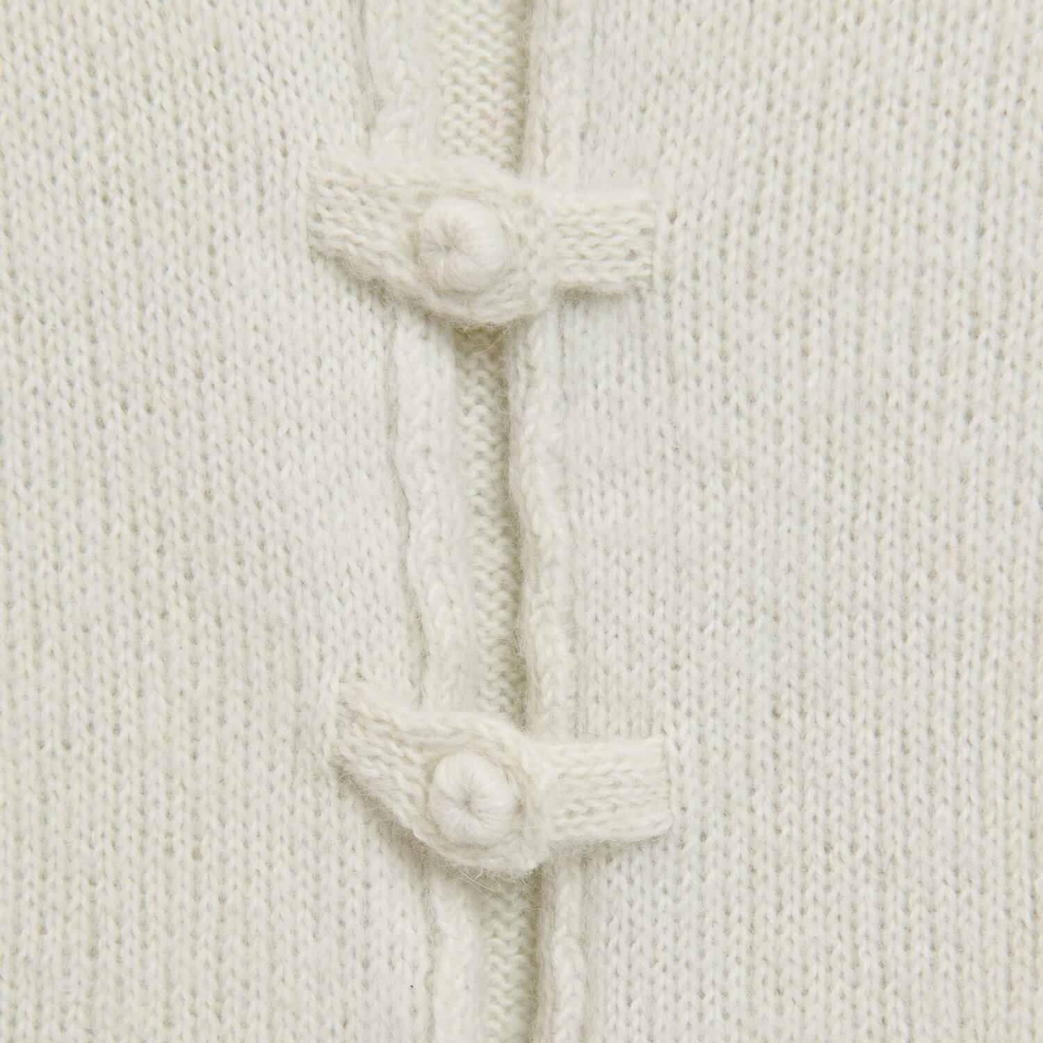 Luxury Merino Alpaca Dream aran zeigt detailreiche Nahaufnahme einer weichen Strickoberfläche mit dekorativen Knebelknöpfen, Rico Design, 50g 125m