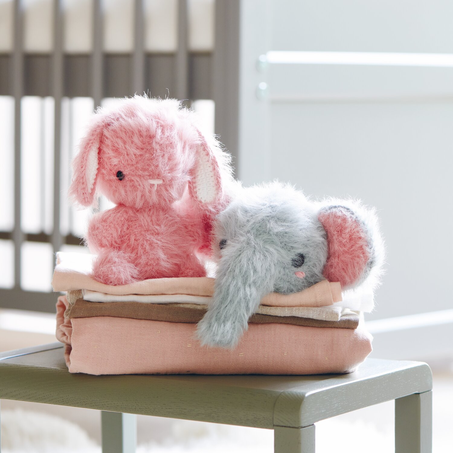Creative Ricorumi dk 25g Farbe Patina von Rico Design Ricorumi Furry Animals: Zwei flauschige Stofftiere, Hase in Pink und Elefant in Patina, auf gefalteten Decken.