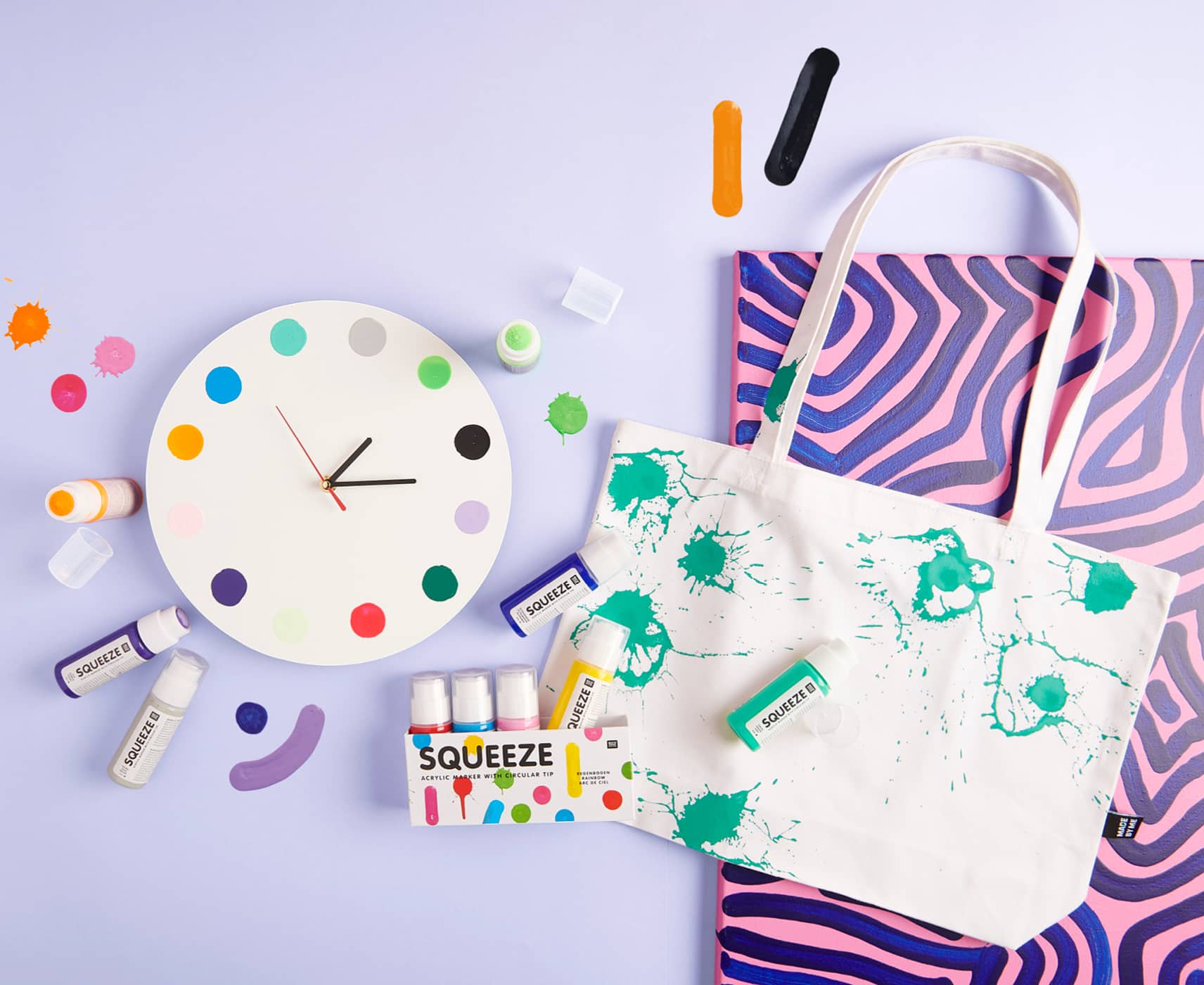 Bemalte Uhr, Tasche und Bild liegen mit Squeeze Markern auf lila Hintergrund ausgelegt