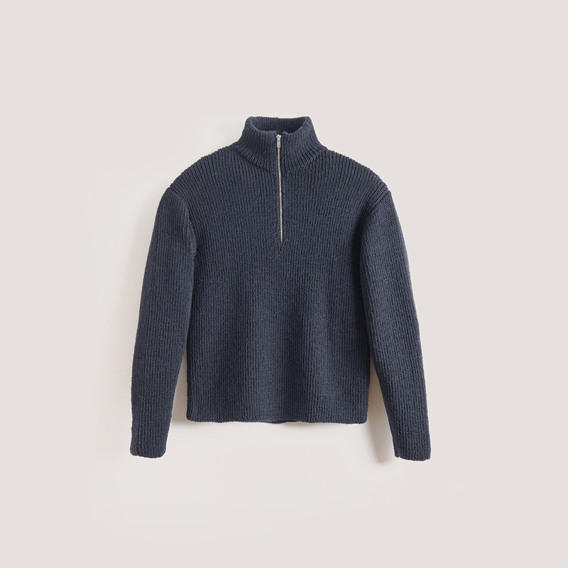 Gestrickter Herrenpullover in Dunkelblau mit Reißverschluss liegt vor grauem Hintergrund.