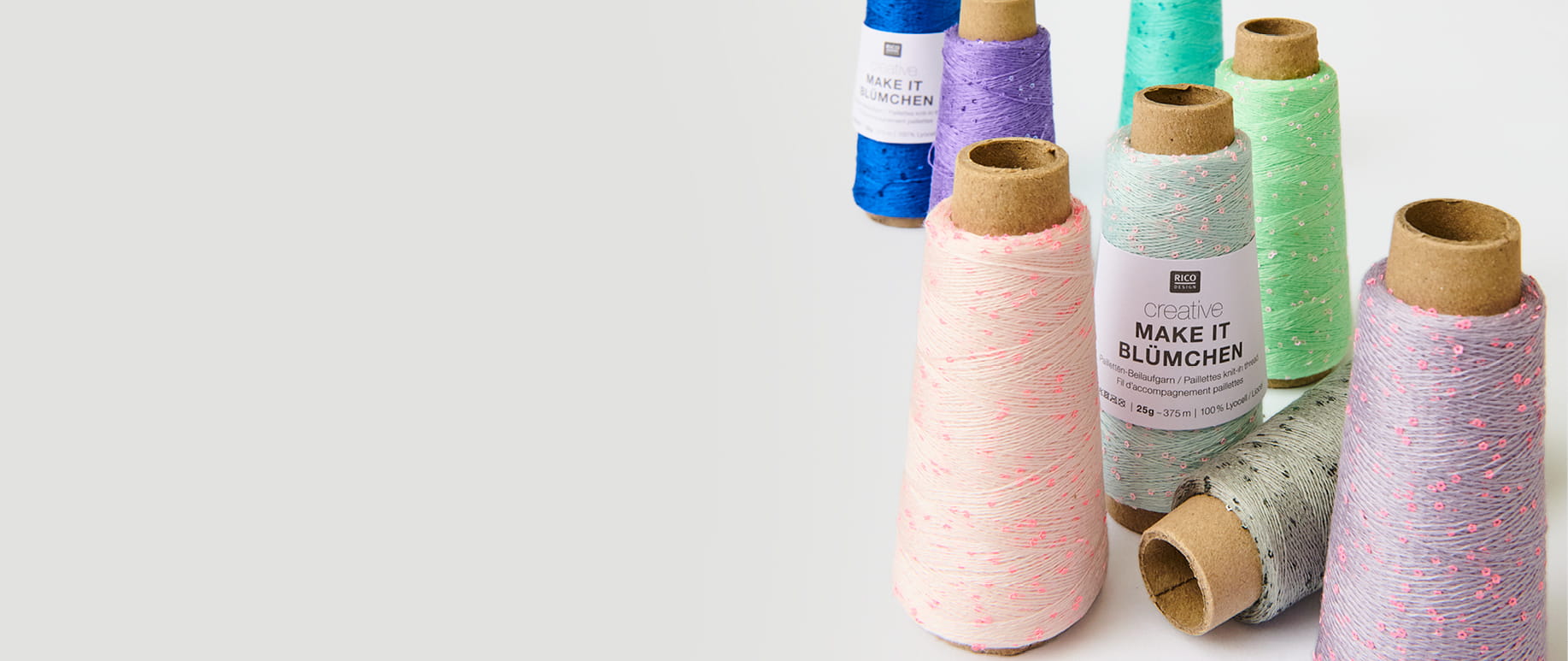 Creative Make it Blümchen in verschiedenen Farben stehen aufgereiht auf hellem Untergrund.