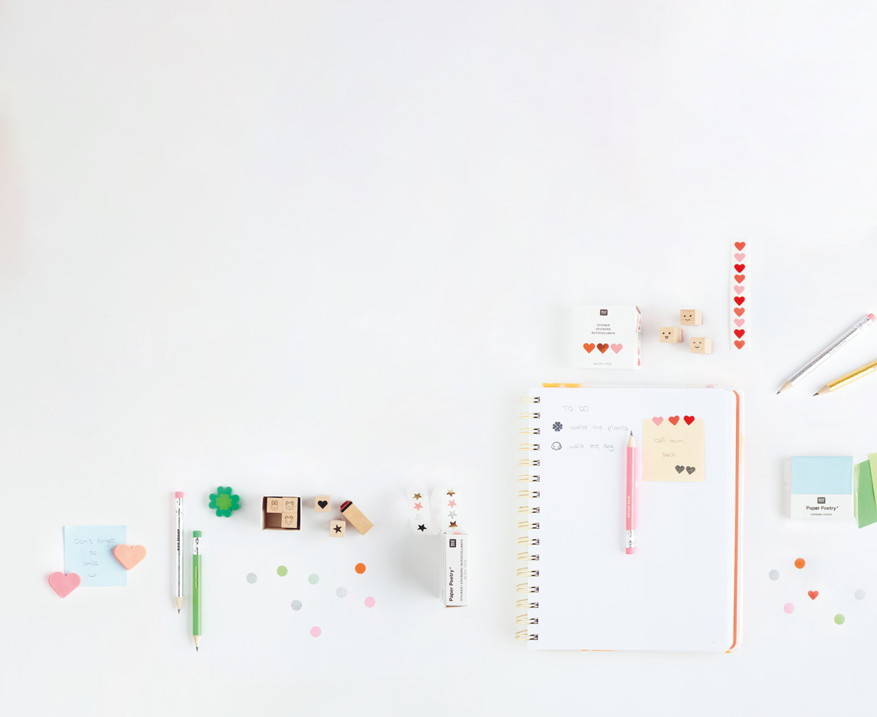 Papeterie-Artikel wie Origami-Papier, Stempel, und Sticker im Mini-Format liegen ausgebreitet auf weißem Hintergrund 