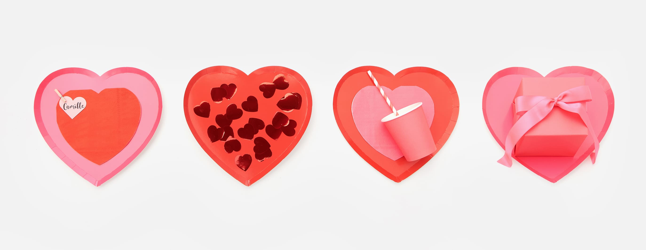 Pappteller in Herzform sind mit Pappbechern, Servietten und Herz-Konfetti dekoriert.