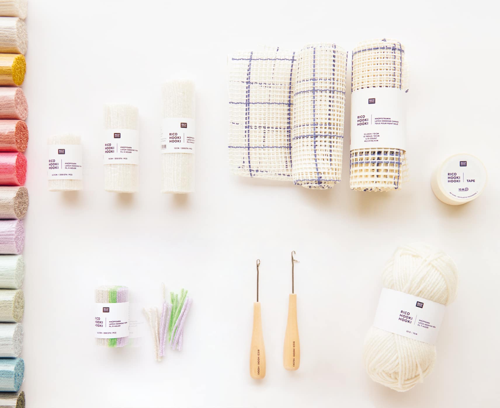 Knüpfgarn in diversen Farben liegen mit Knüpfhaken, Stramin und Knüpfmaterial auf weißem Hintergrund