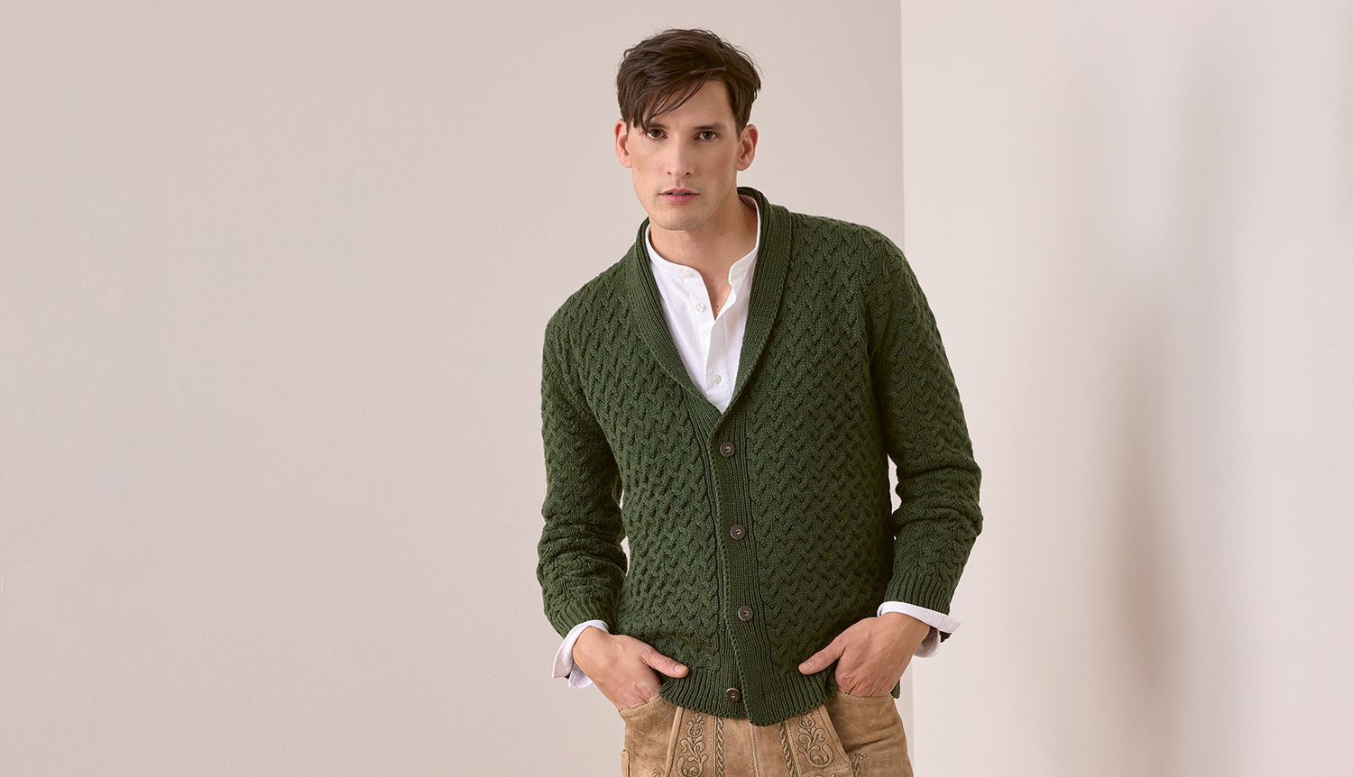 Trachtenjacke aus Essentials Merino Plus dk, grün, mit Knopfleiste, getragen von einem Mann vor neutralem Hintergrund.