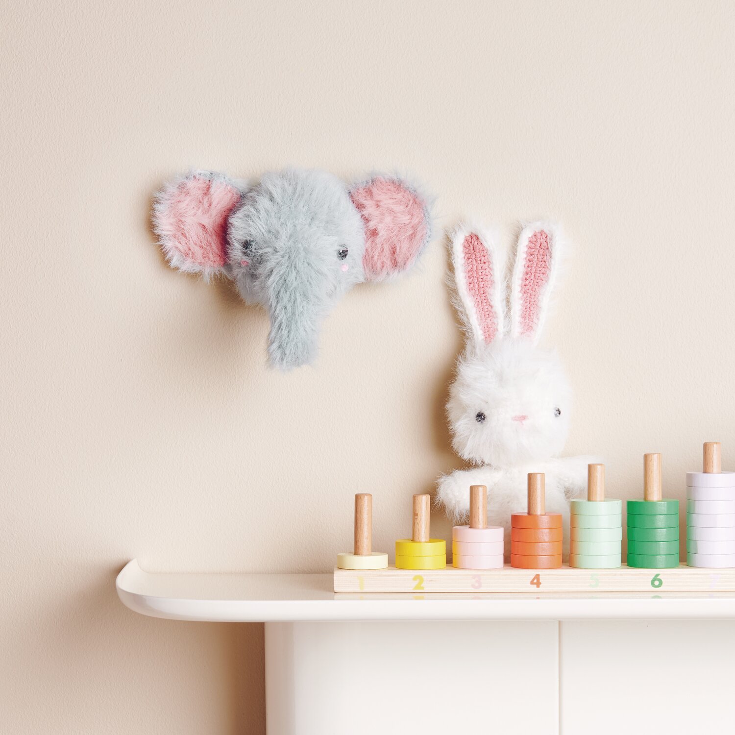 Creative Ricorumi dk 25g Farbe Patina von Rico Design Ricorumi Furry Animals: Flauschiger Elefant und Hase aus Wolle, dekorativ auf Regal mit bunten Holzspielzeugen.