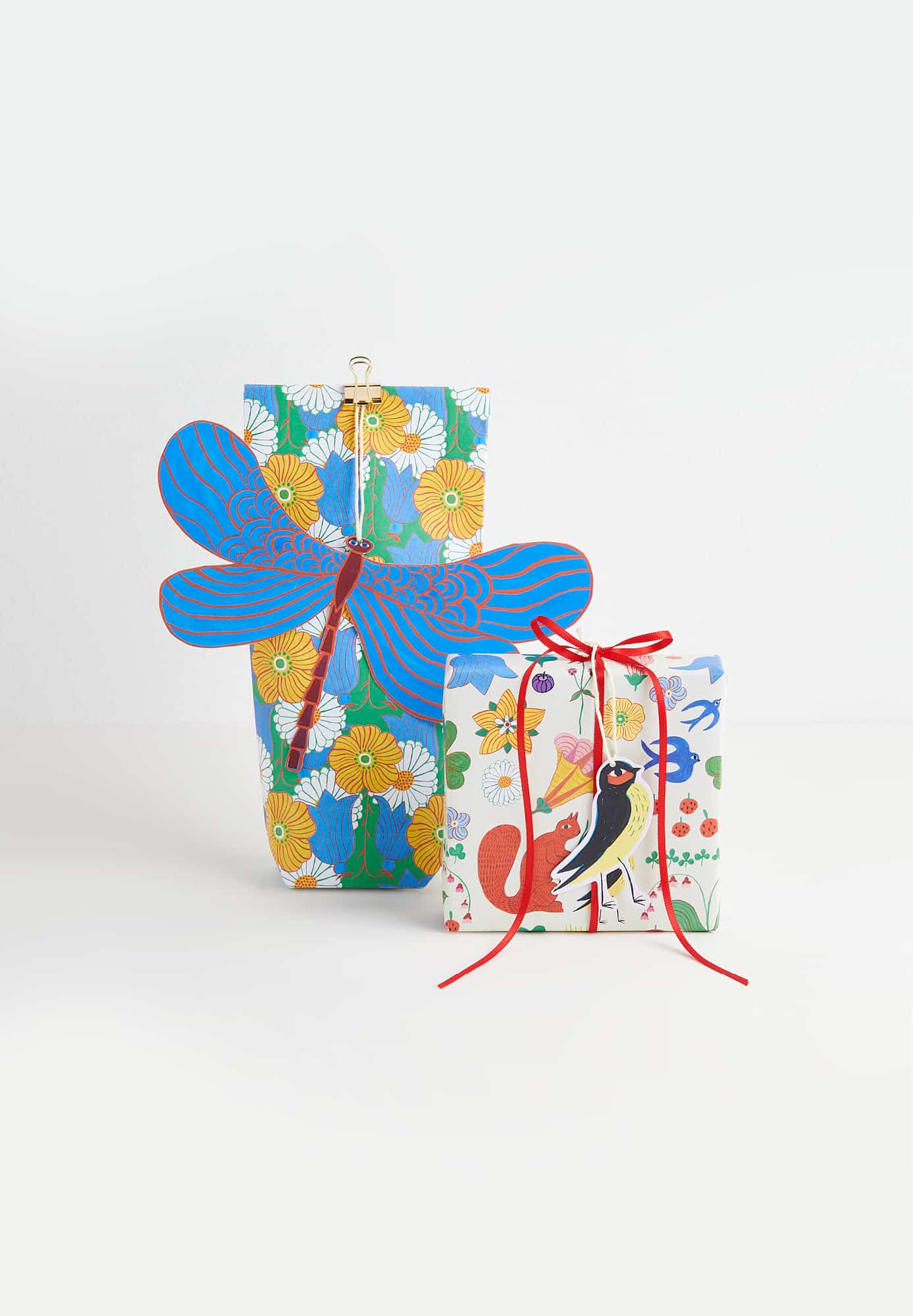 Zwei verpackte Geschenk mit bunt gemustertem Geschenkpapier und Geschenkanhänger in Libellenform