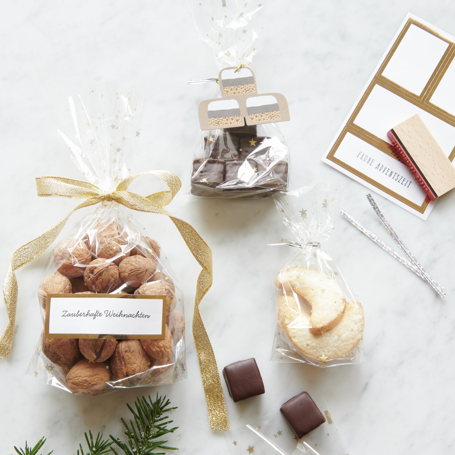 Paper Poetry Papieretiketten Gold 4 Stück auf einem Tisch mit verpackten Keksen und Nüssen.