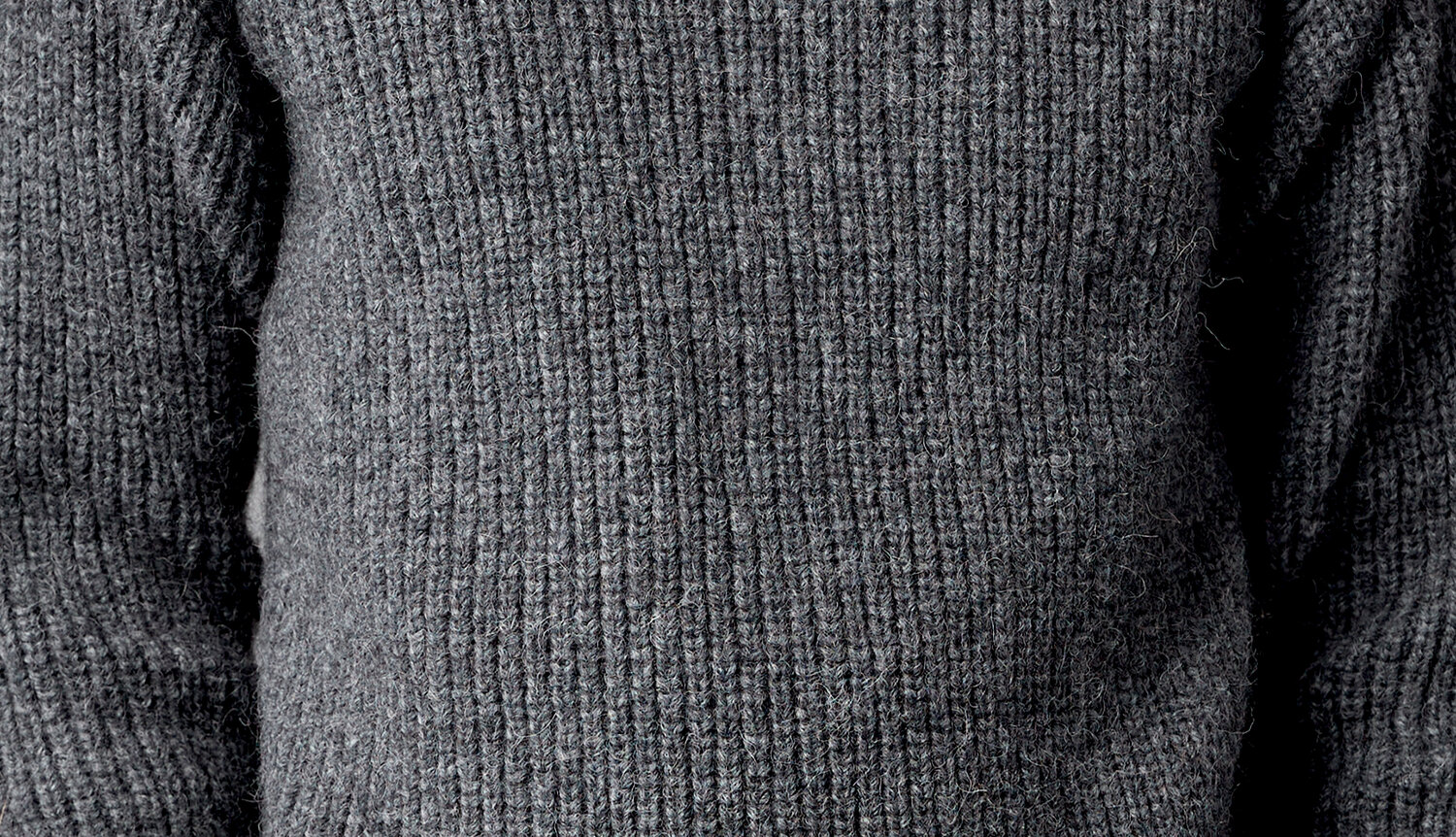 Strickanleitung Herrenpullover aus Alpaca Superfine aran zeigt einen grob gerippten, langärmligen Feinstrickpullover in meliertem Dunkelgrau für moderne Herrengarderobe