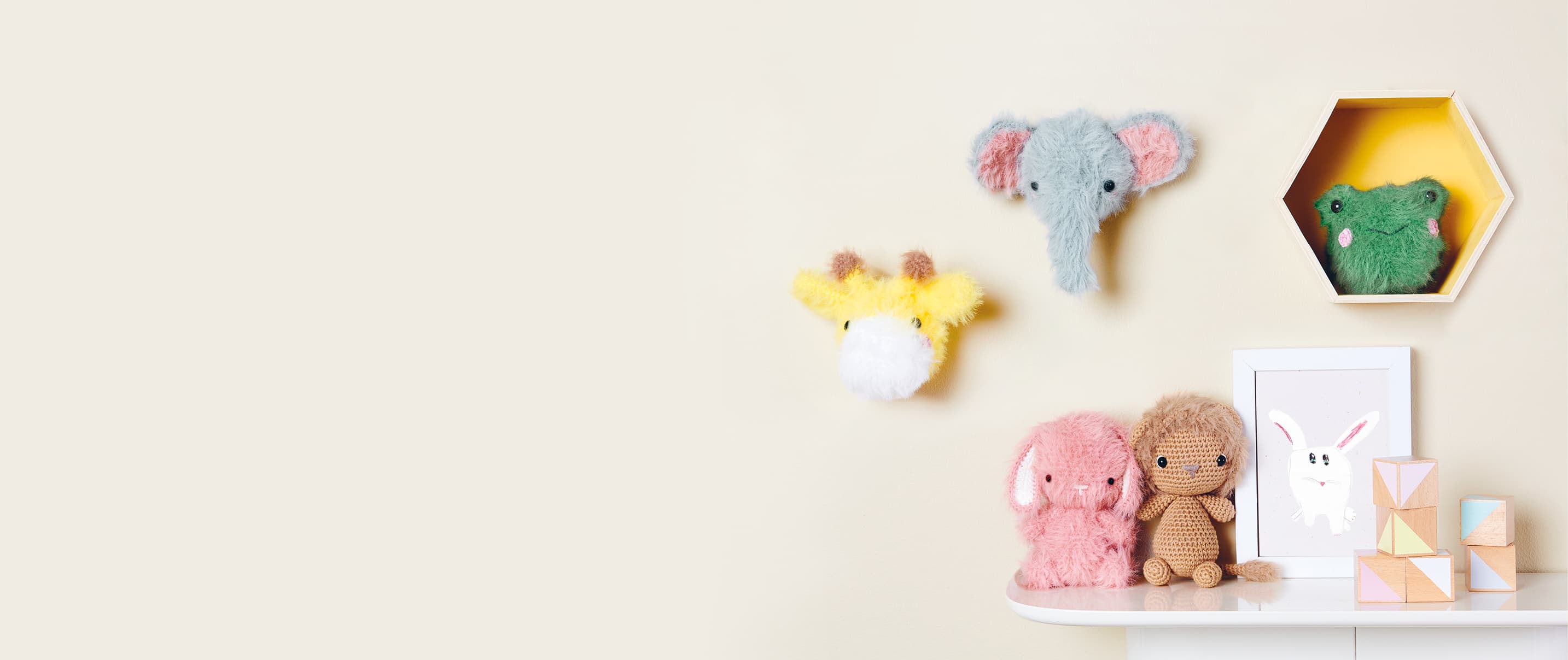 Gehäkelte Tiere mit flauschigem Fell sind an einer Wand und auf einem Regal dekoriert.