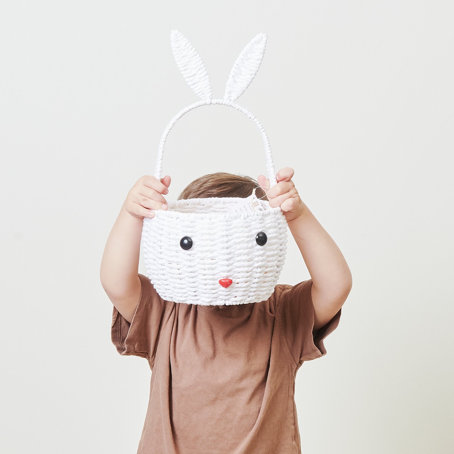 Osterkorb Hase: Weißer Korb in Hasenform von Rico Design, gehalten von Kind in braunem Shirt.
