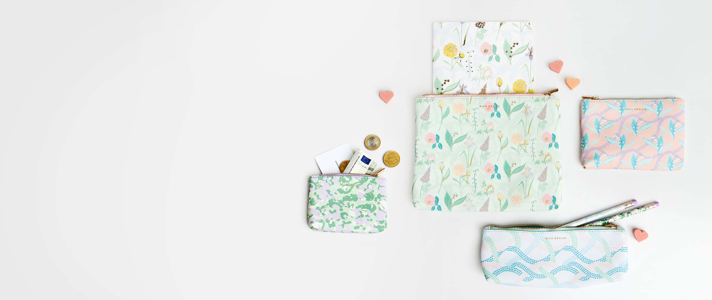 Pastellfarbene Etuis in verschiedenen Größen und floralen und abstrakten Mustern liegen auf grauem Hintergrund.