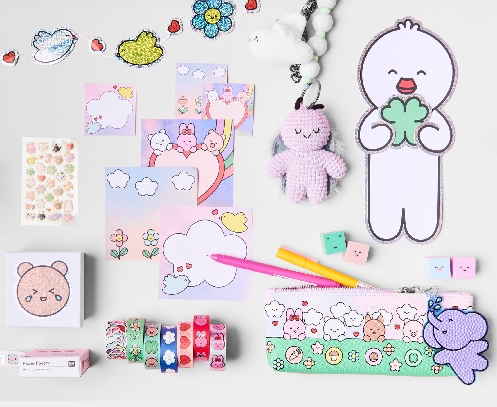 Diverse Papeterie-, Dekoartikel und Häkelfiguren mit liebevoll illustrierten Tierfiguren liegen angeordnet auf grauem Hintergrund. 