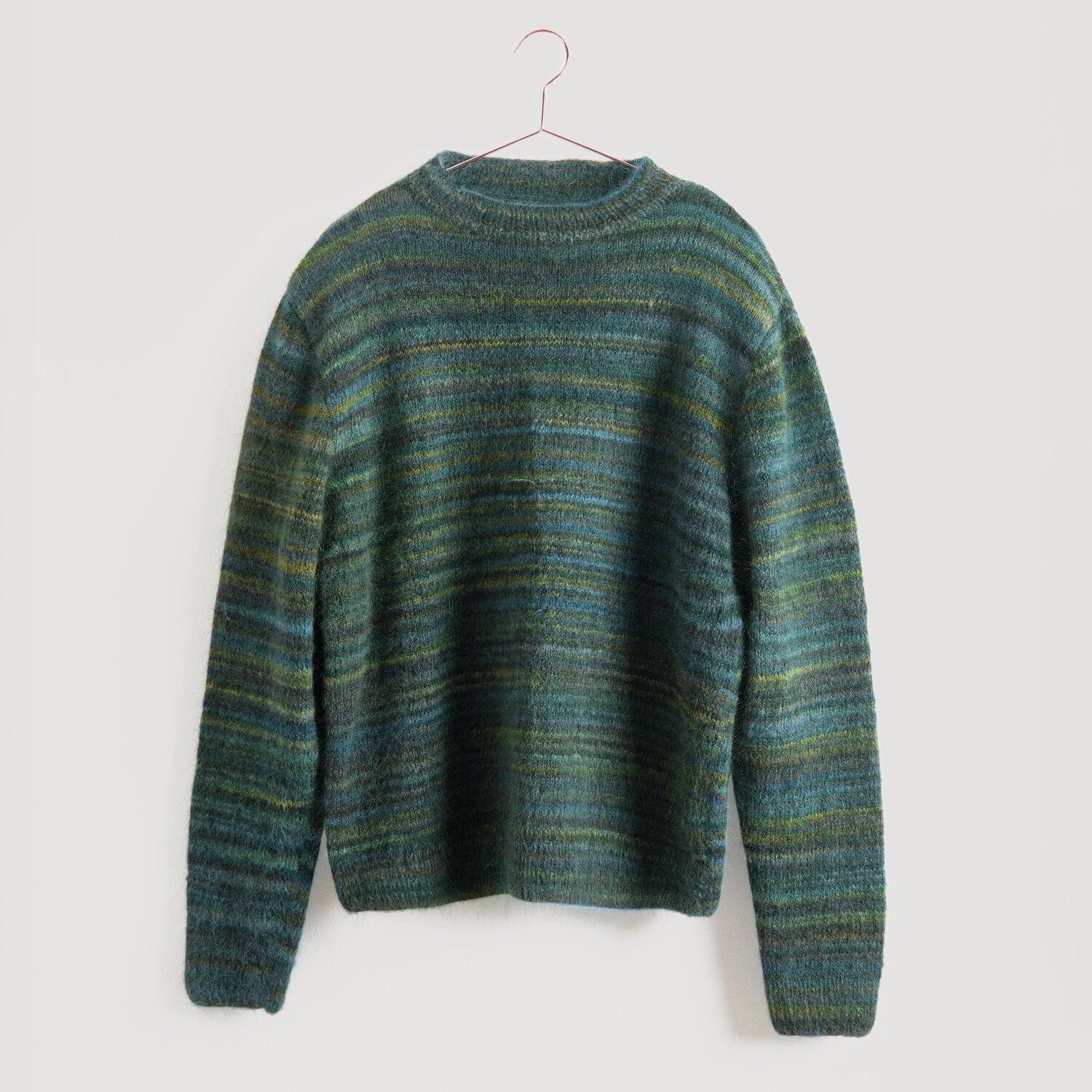 Grüner gestreifter Pullover von Modell Legeware, hängend an einem Kleiderbügel. Der Pullover hat horizontale Streifen in verschiedenen Grüntönen und ist ideal für kühle Tage.