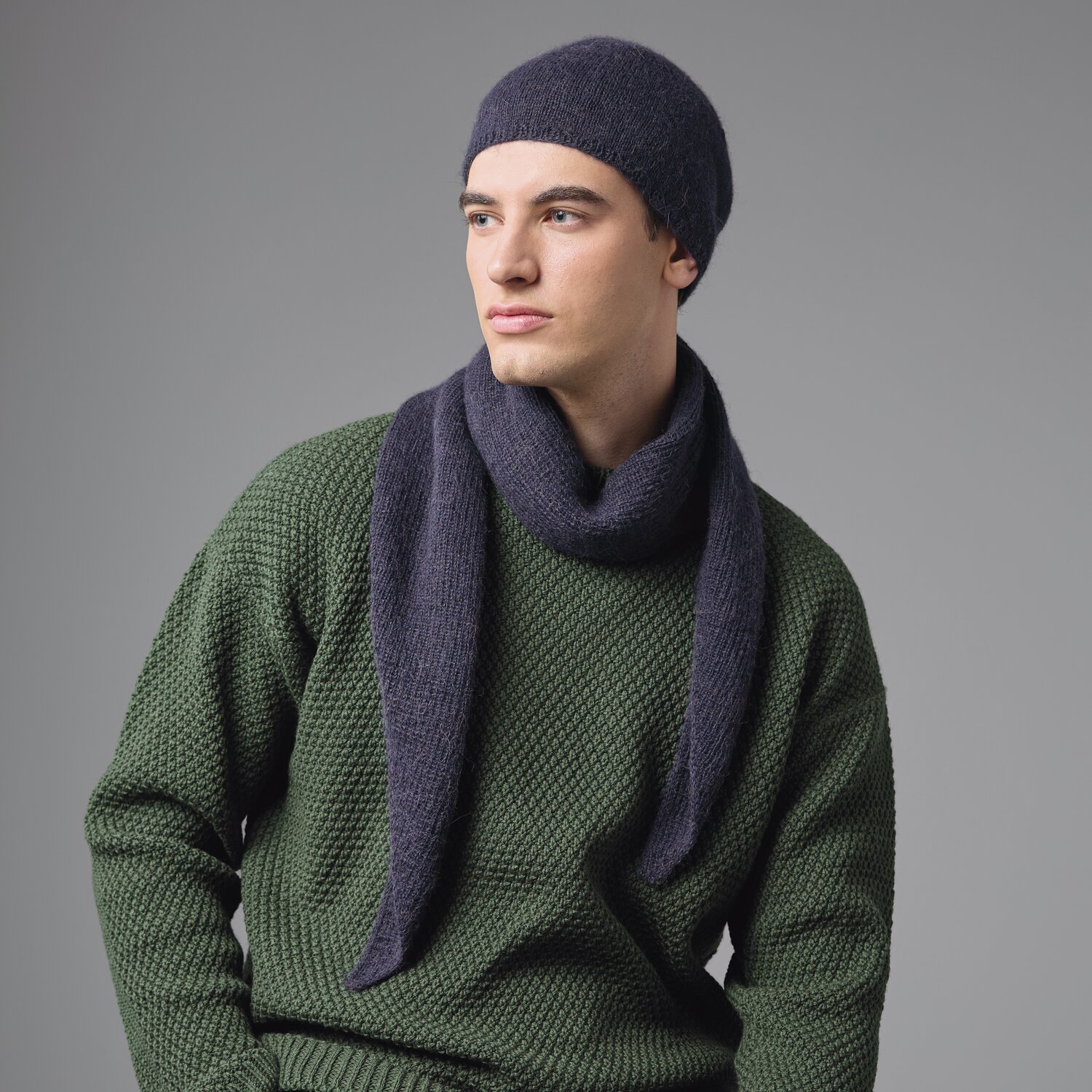 Strickset Mütze Modell 03 aus Made by Me Men No. 3 von Rico Design Strickset Mütze Modell 03: Mann trägt dunkelblaue Mütze und Schal, grüner Pullover, stilvoll.