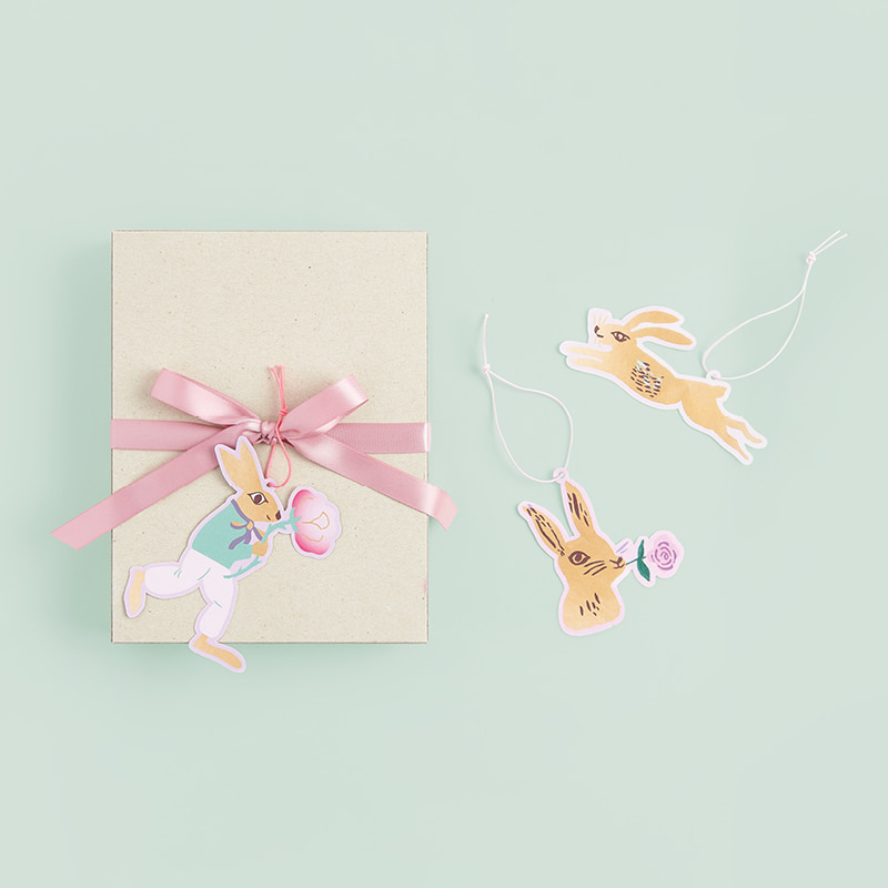 Geschenkanhänger in Hasenform hängen an einem Geschenk und liegen verteilt daneben. 