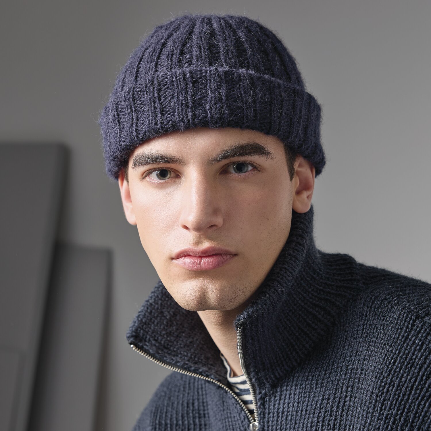 Strickset Mütze Modell 09 aus Made by Me Men No. 3 von Rico Design Strickset Mütze Modell 09 aus Made by Me Men No. 3: Dunkelblaue Mütze auf Mann mit passendem Strickpullover.