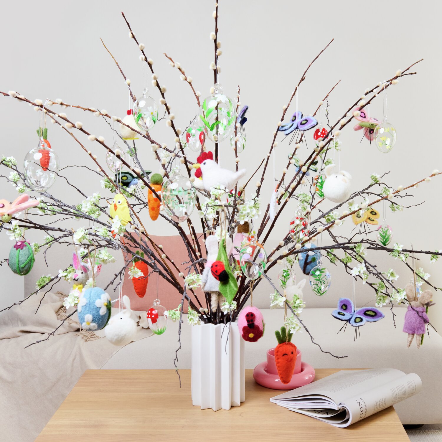 Glas Eier Blumenwiese handbemalt 4 Stück dekorieren einen Osterstrauß mit bunten Anhängern in einer weißen Vase auf einem Holztisch.