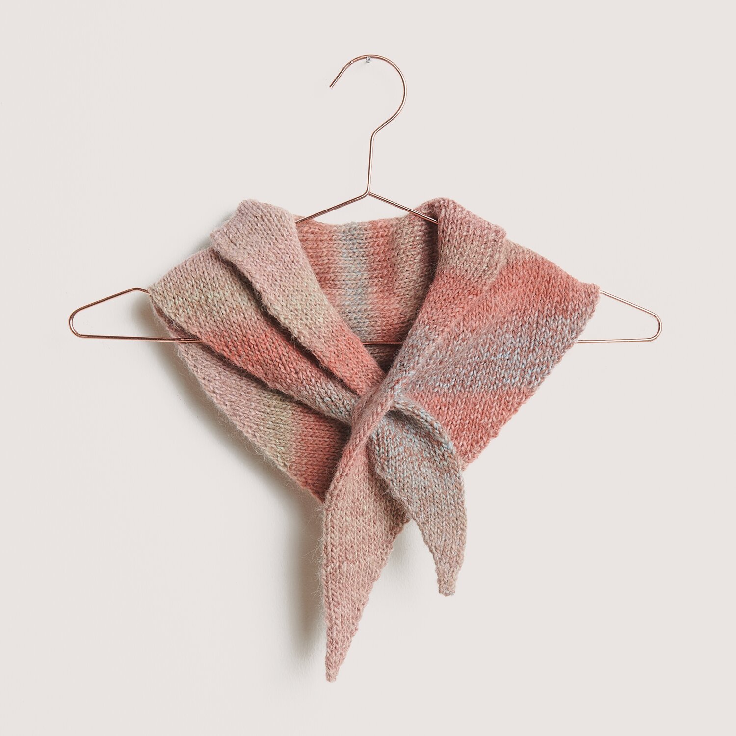 Creative Melange Alpaca Wonderball dk Schal in sanften Frühlingsfarben auf einem Kleiderbügel.