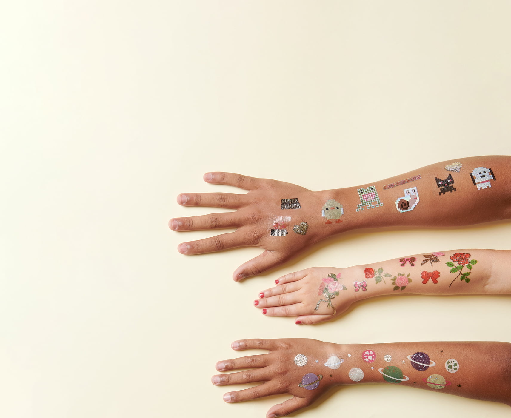 Arme sind mit temporären Tattoos beklebt in verschiedenen Designs mit Rosen, Tier und Planet-Motiven.